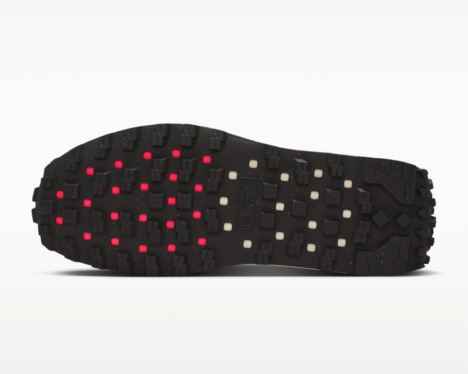 Black rubber shoe sole with red and white square accents and textured tread pattern.