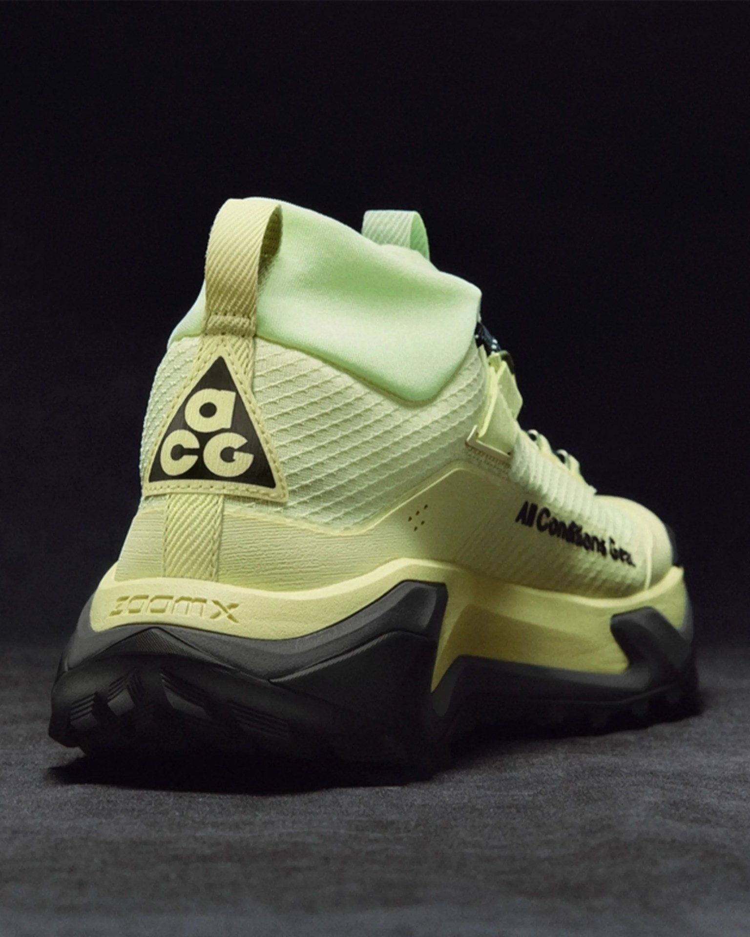 Light green and black Nike ACG hiking shoe with textured upper and thick sole on dark surface.