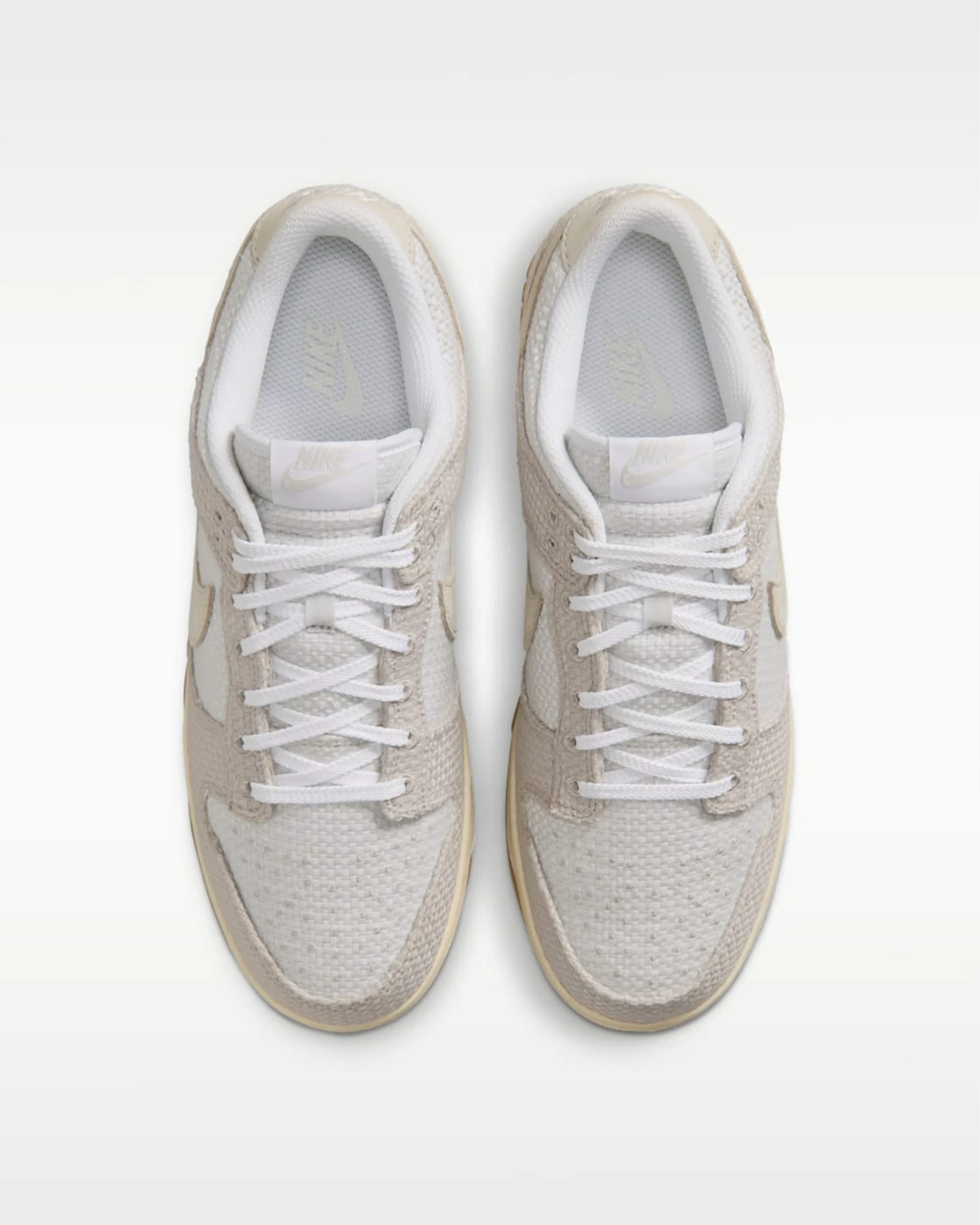Pair of beige and white Nike sneakers with white laces viewed from above on a white background.