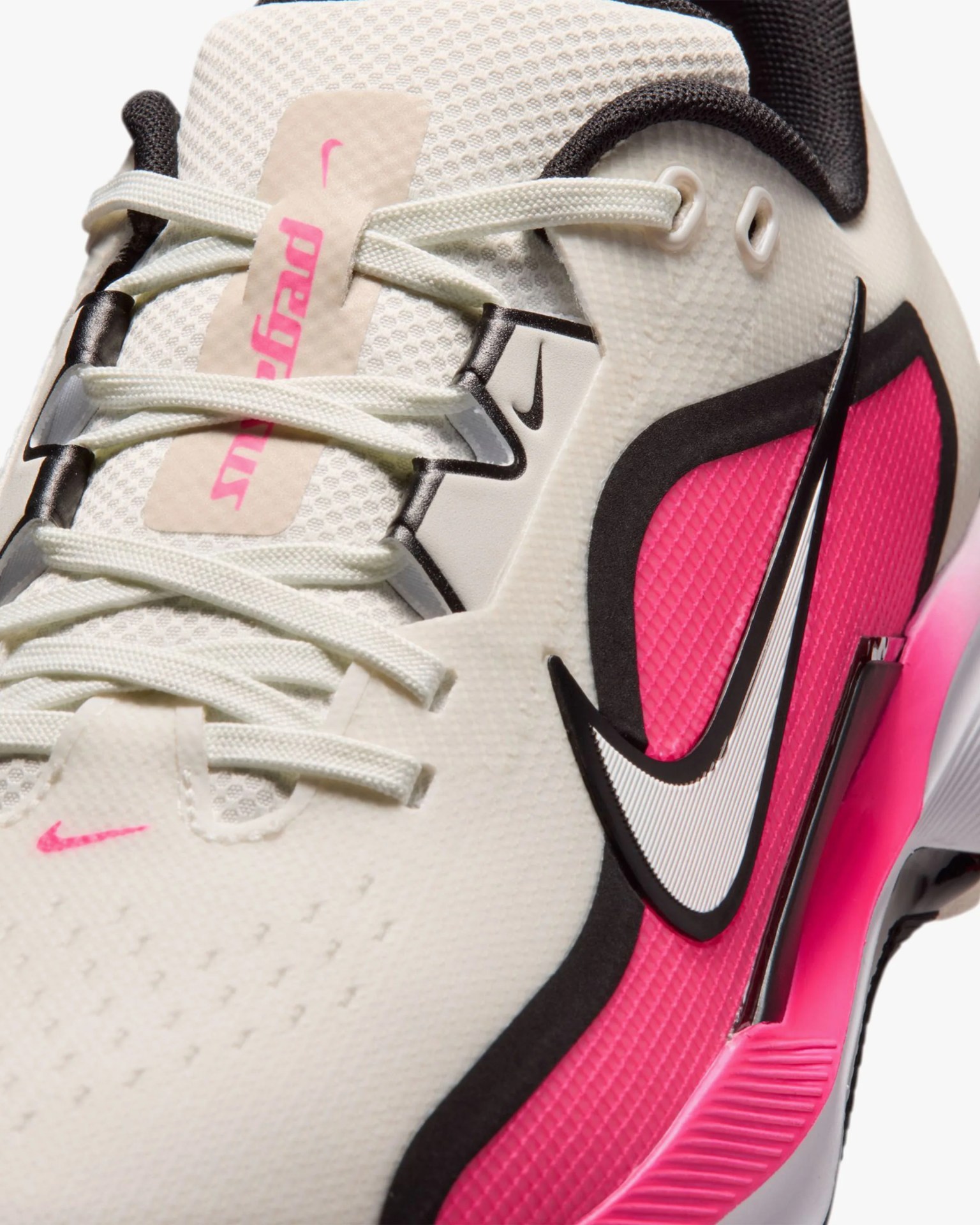 Close-up of a white Nike sneaker with pink and black accents and white laces.