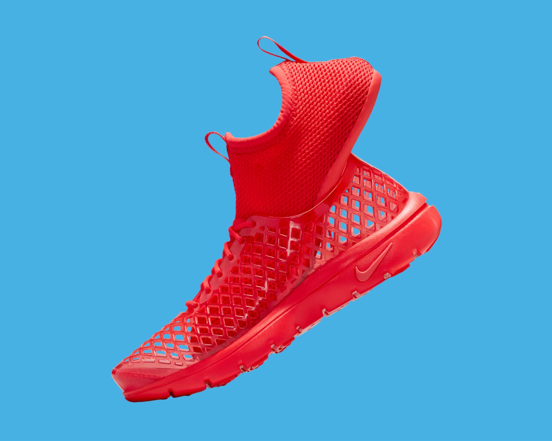 Bright red Nike sneaker with a mesh upper and lattice design on a blue background.