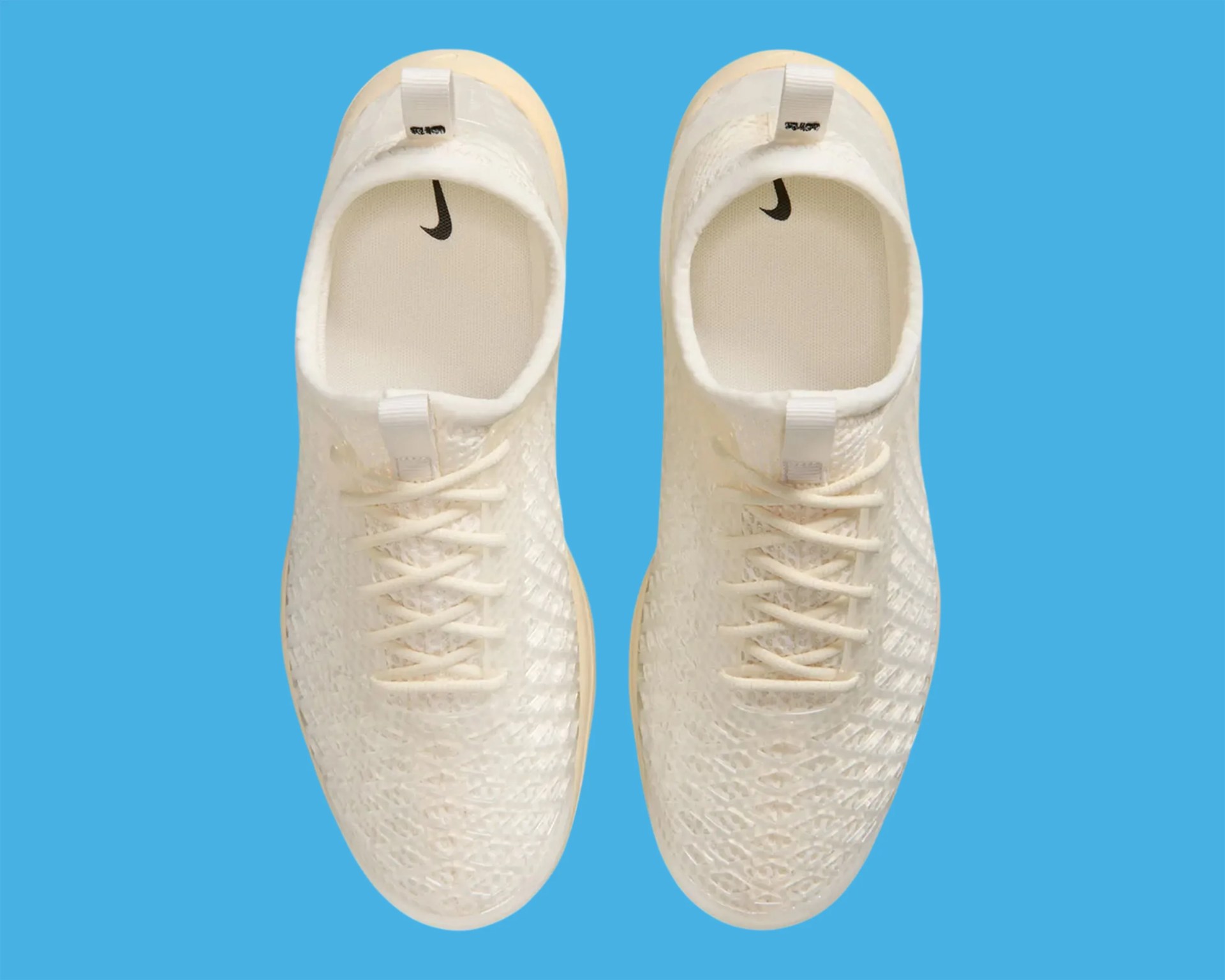 Pair of cream-colored Nike sneakers with woven texture and black swoosh logo inside, on blue background.