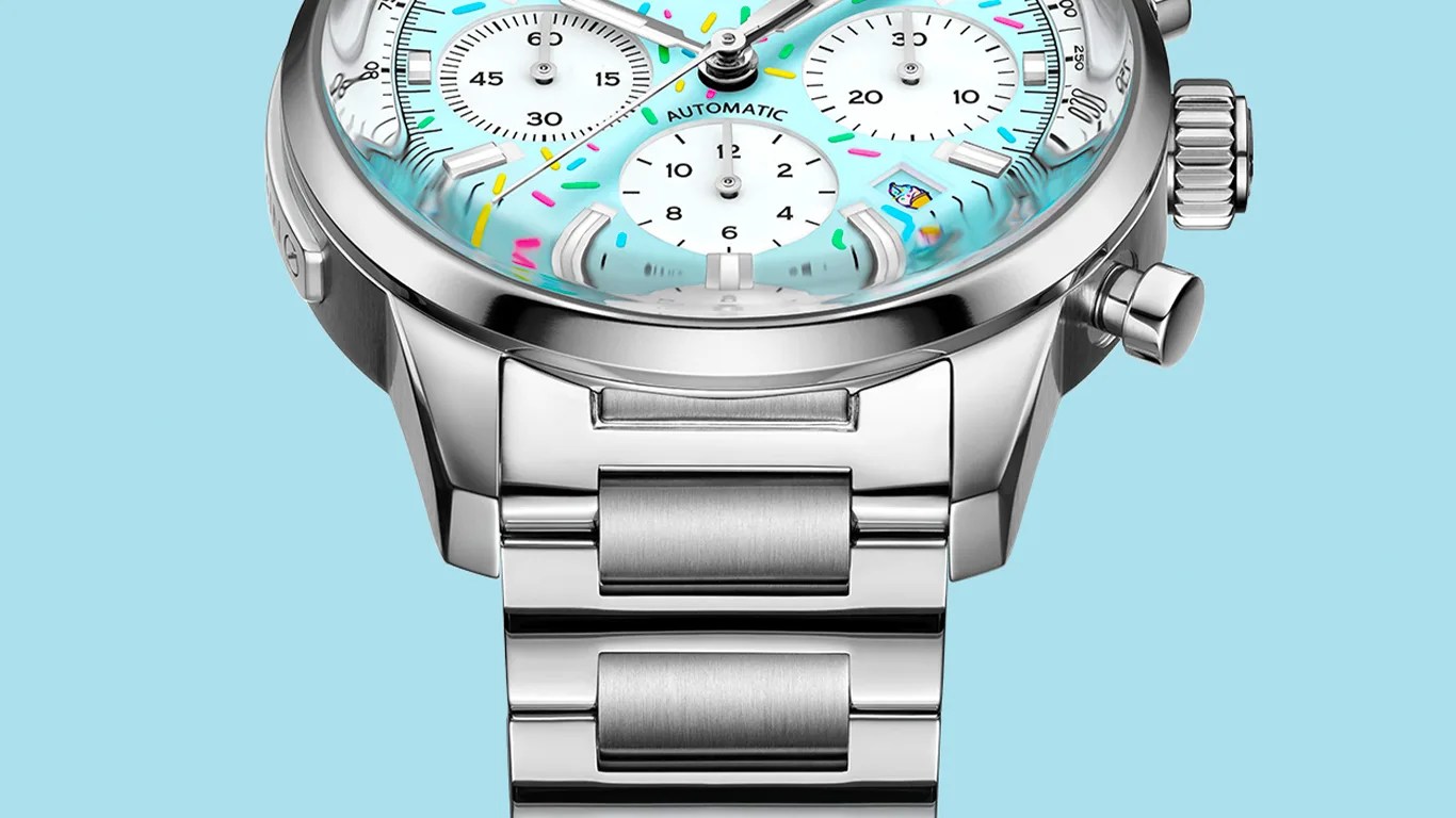 Close-up of a silver stainless steel watch with a light blue dial featuring colorful confetti-like accents and three white subdials.