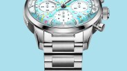 Close-up of a silver stainless steel watch with a light blue dial featuring colorful confetti-like accents and three white subdials.