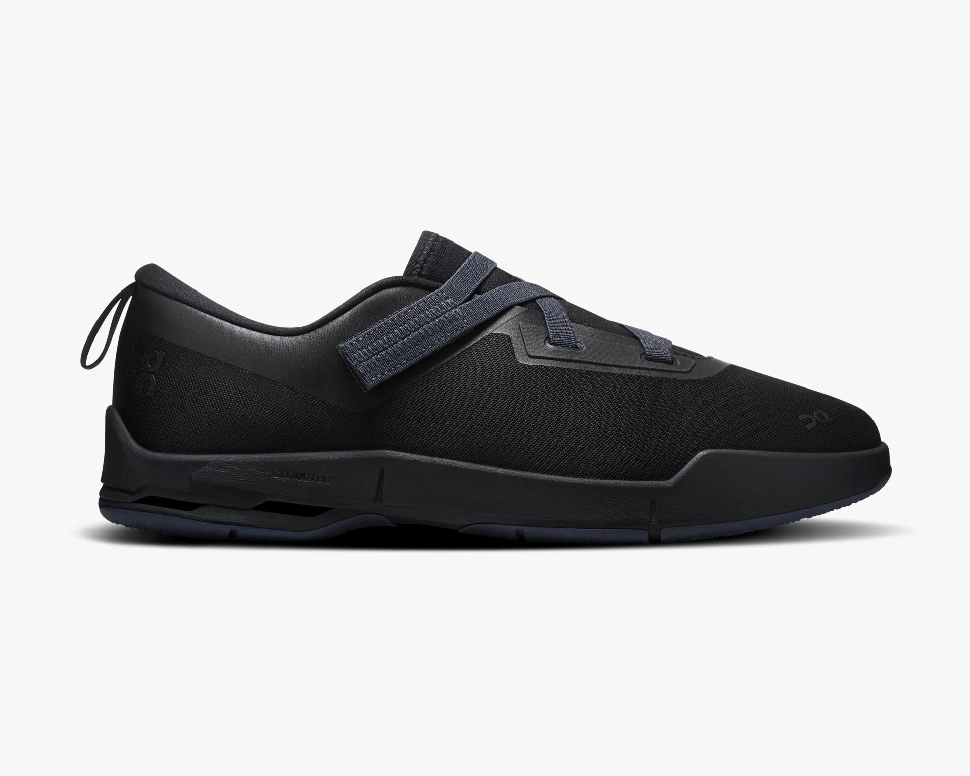 Black low-top athletic shoe with mesh upper, dark blue strap and laces, and cushioned sole.