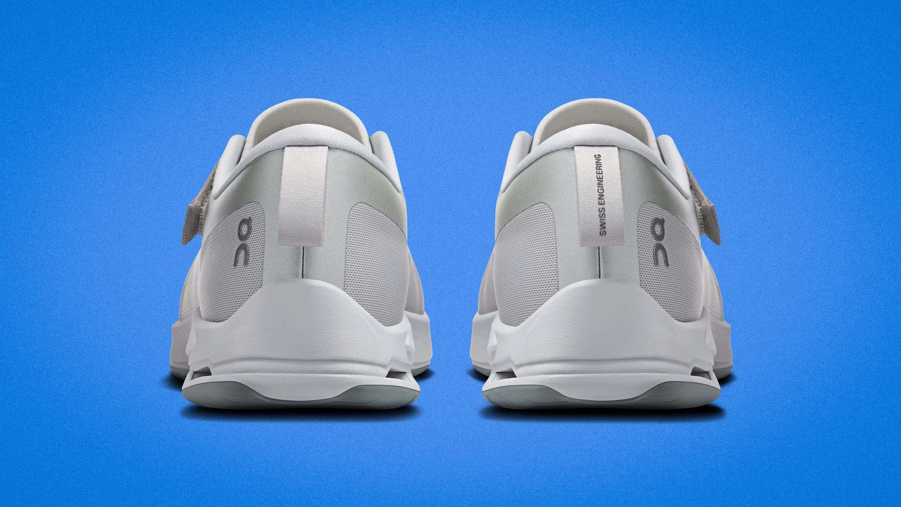 Pair of white athletic shoes with "Swiss Engineering" text on heel tabs against a blue background.