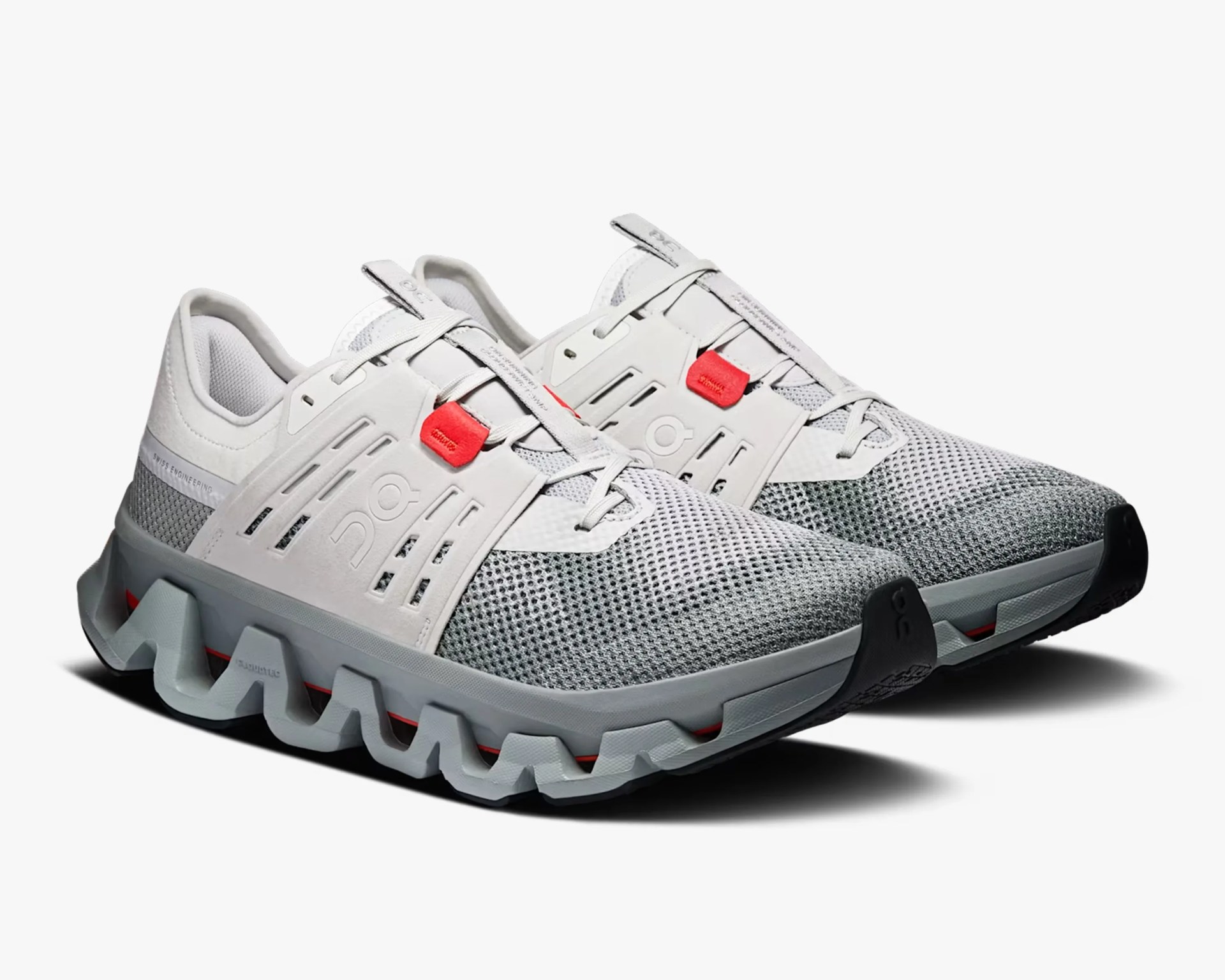 Pair of white and gray athletic shoes with red accents and a distinctive zigzag sole design.