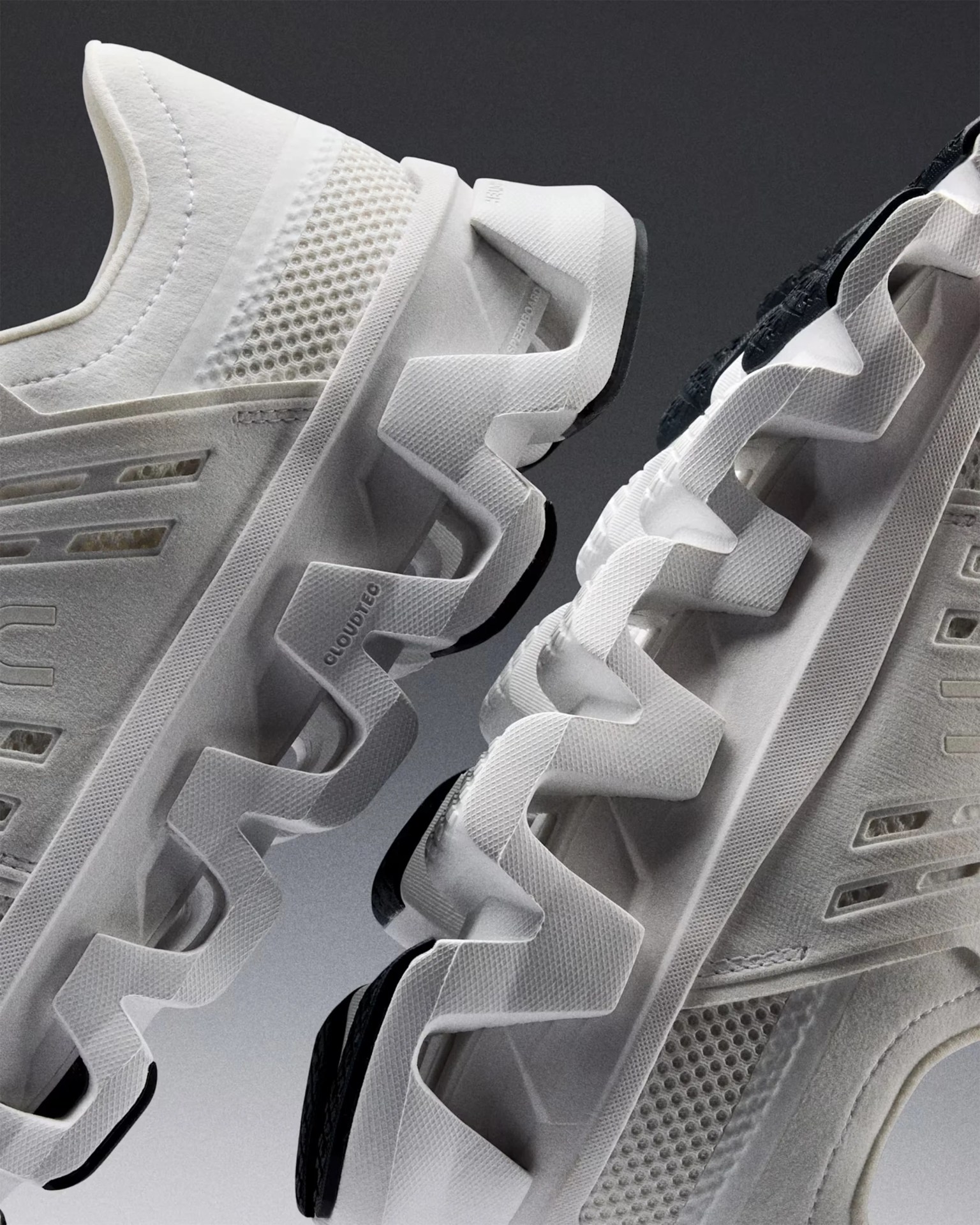 Close-up of white athletic shoes with zigzag-patterned soles and mesh fabric details.