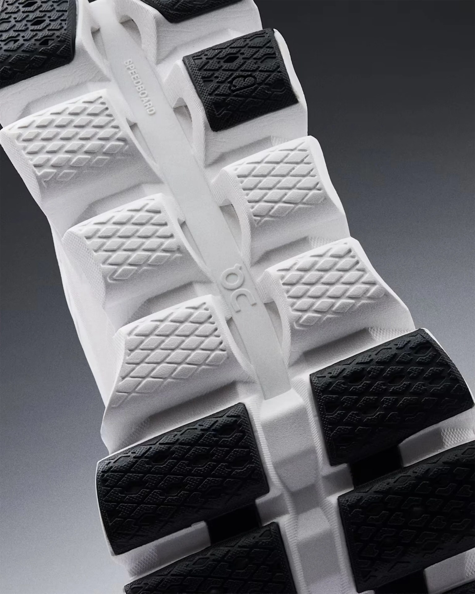 Close-up of a white and black textured shoe sole with "SPEEDBOARD" and "OC" embossed on the center strip.