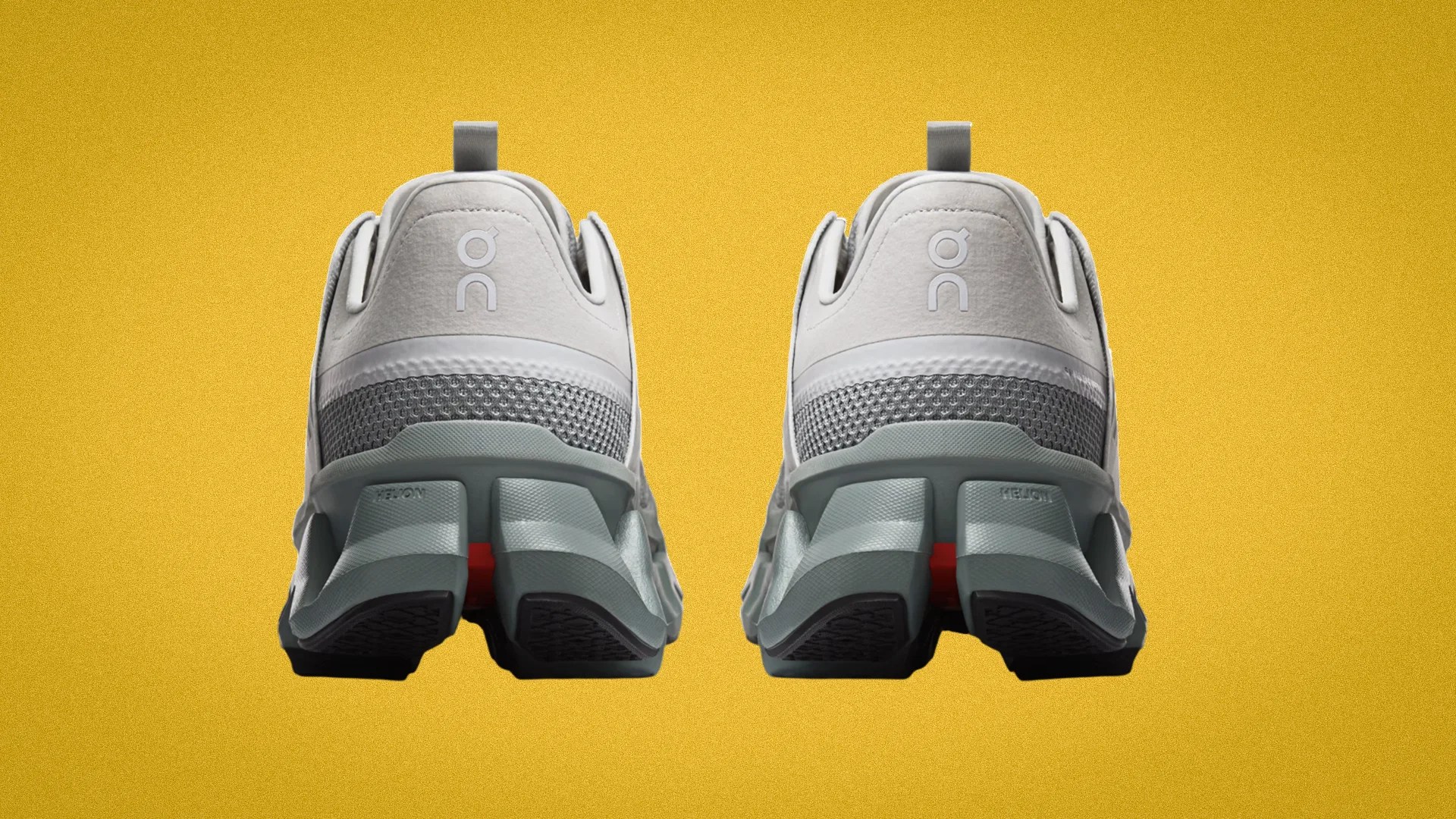 Pair of light gray and white athletic shoes with segmented soles shown from the back on a yellow background.