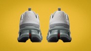 Pair of light gray and white athletic shoes with segmented soles shown from the back on a yellow background.