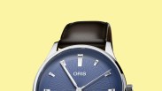 Close-up of an Oris wristwatch with a blue textured dial, silver hands and markers, and a black leather strap.