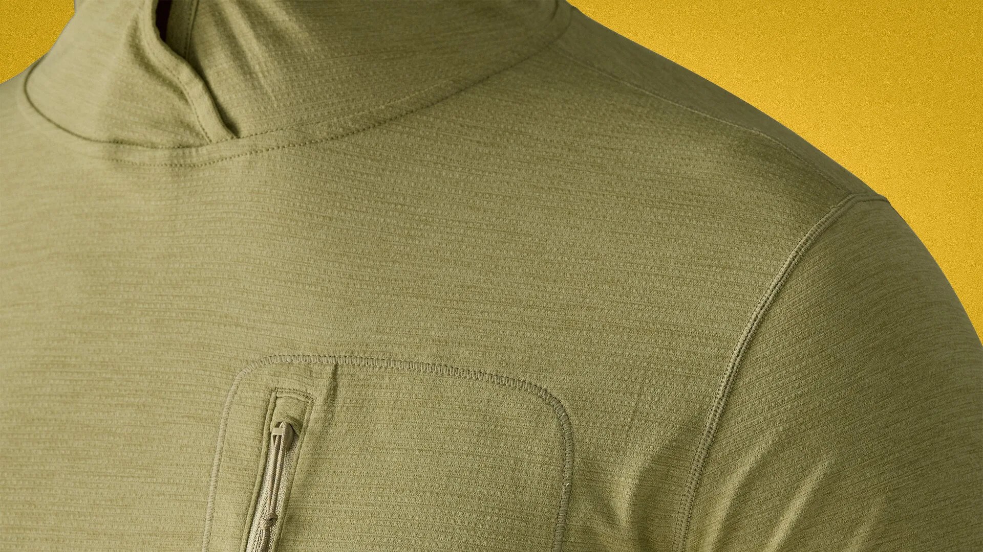 Close-up of an olive-green textured hoodie with a zippered chest pocket against a yellow background.