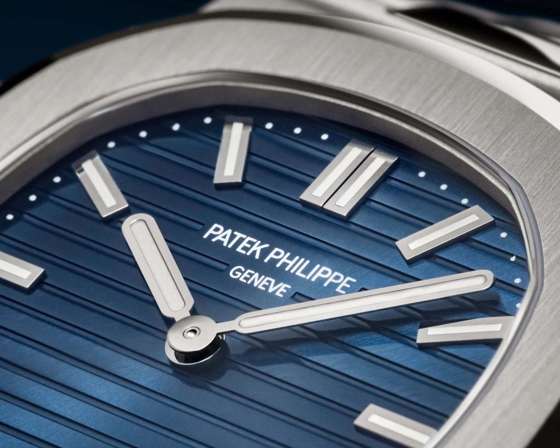 Close-up of a Patek Philippe watch face with a blue textured dial and silver hour markers and hands.