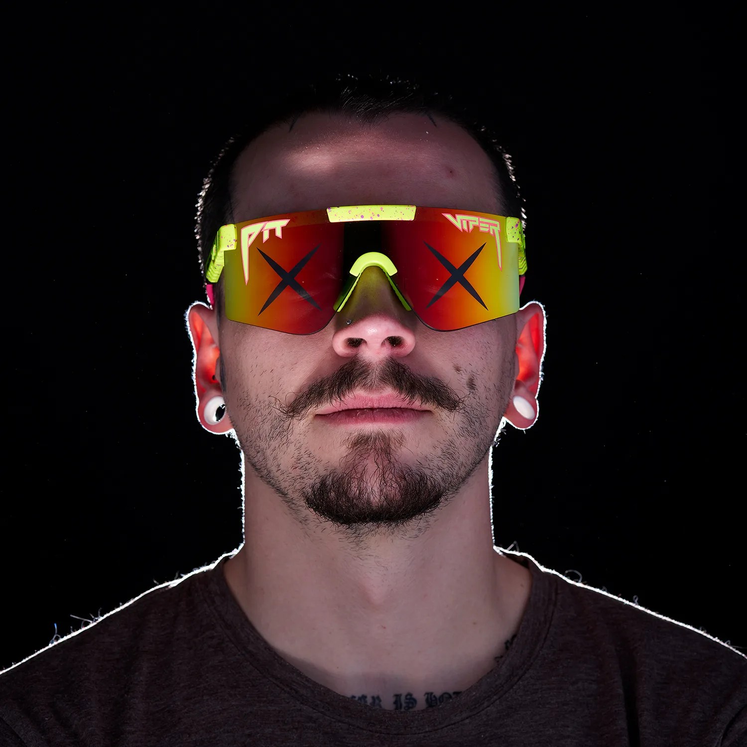 Man wearing large neon yellow and red reflective sports sunglasses with "PIT VIPER" text on the lenses against a black background.
