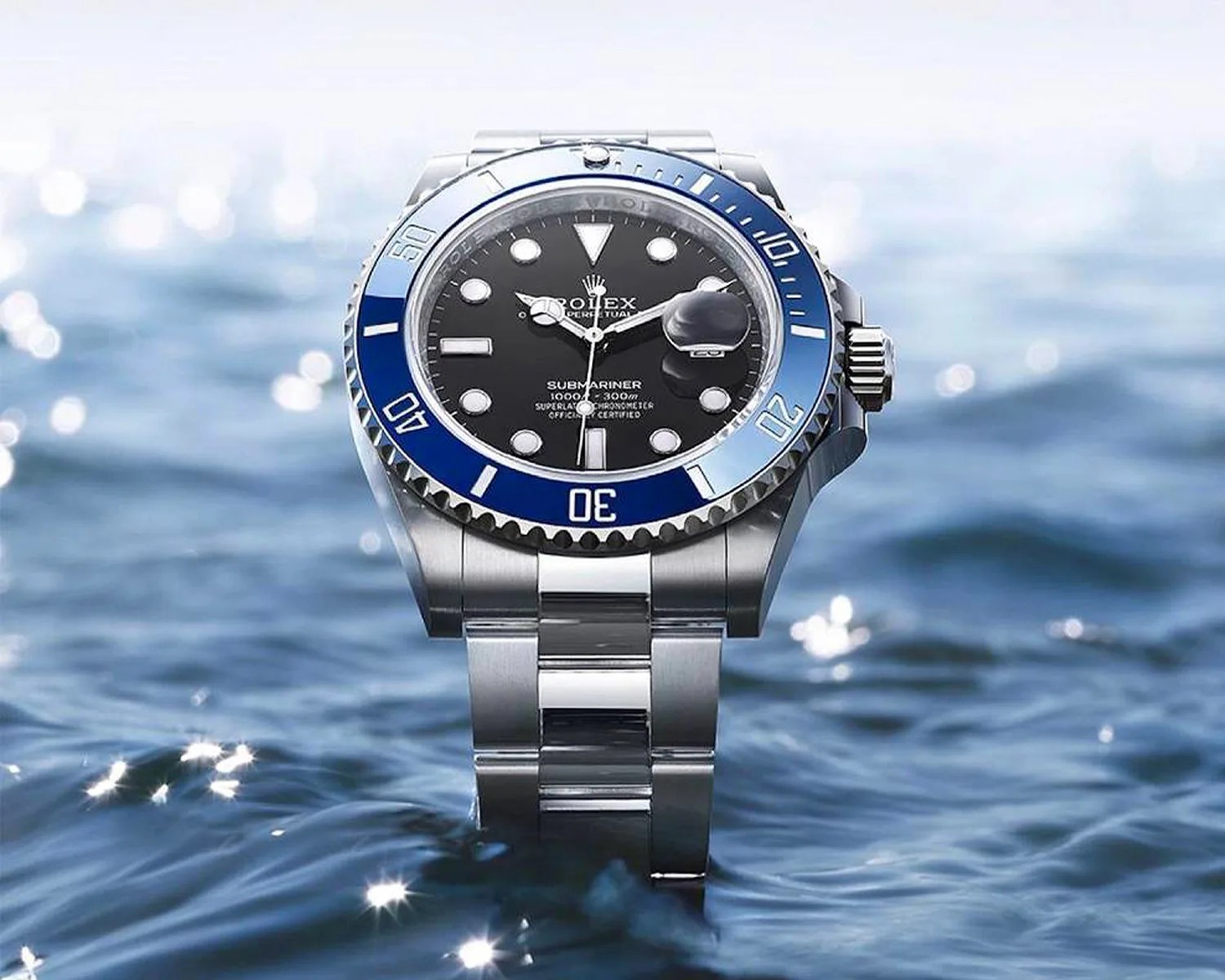 Stainless steel Rolex Submariner watch with black dial and blue bezel floating on water.