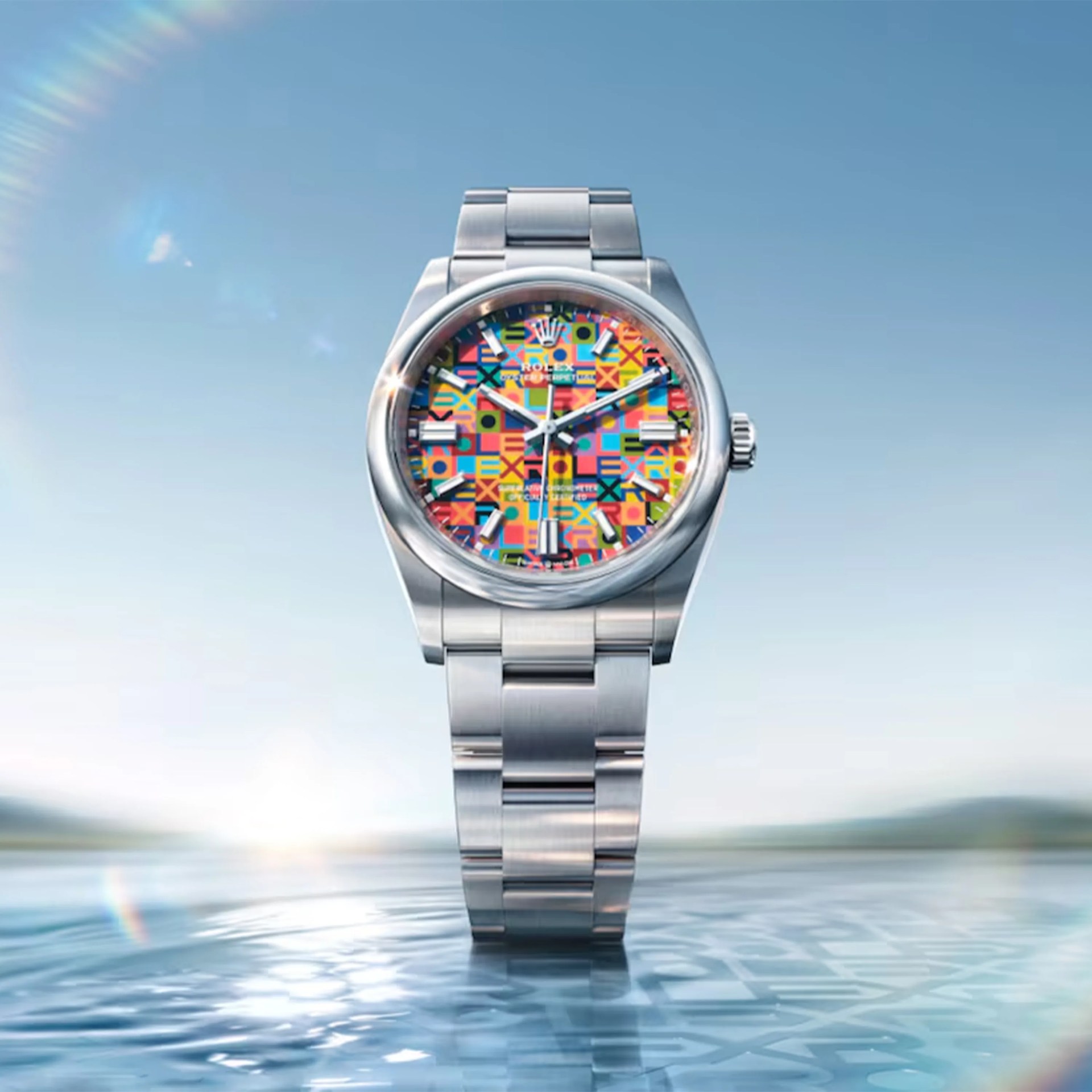 Stainless steel Rolex watch with a colorful geometric patterned dial standing on reflective water surface.