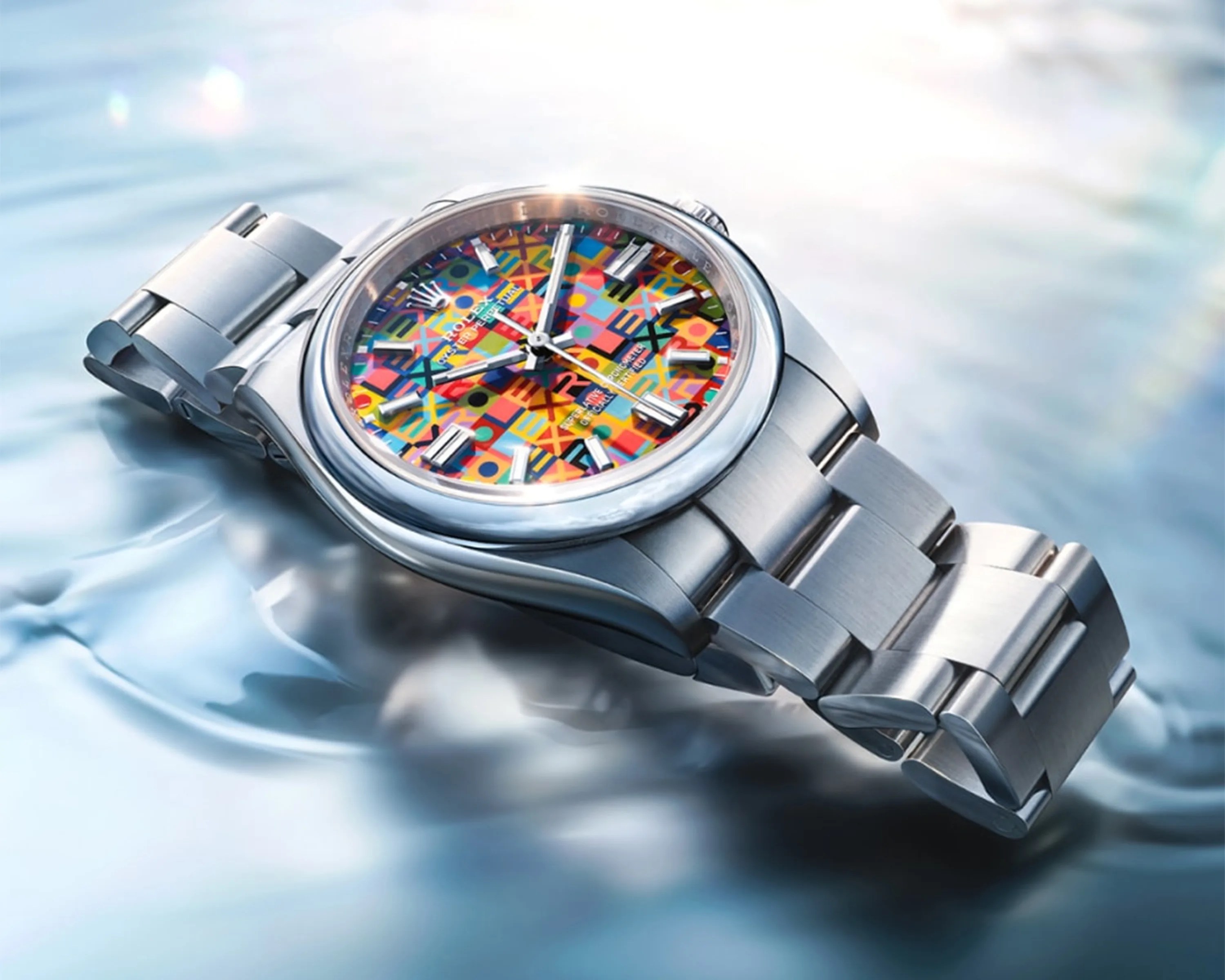 Silver metal Rolex watch with a colorful geometric patterned dial resting on a reflective surface.
