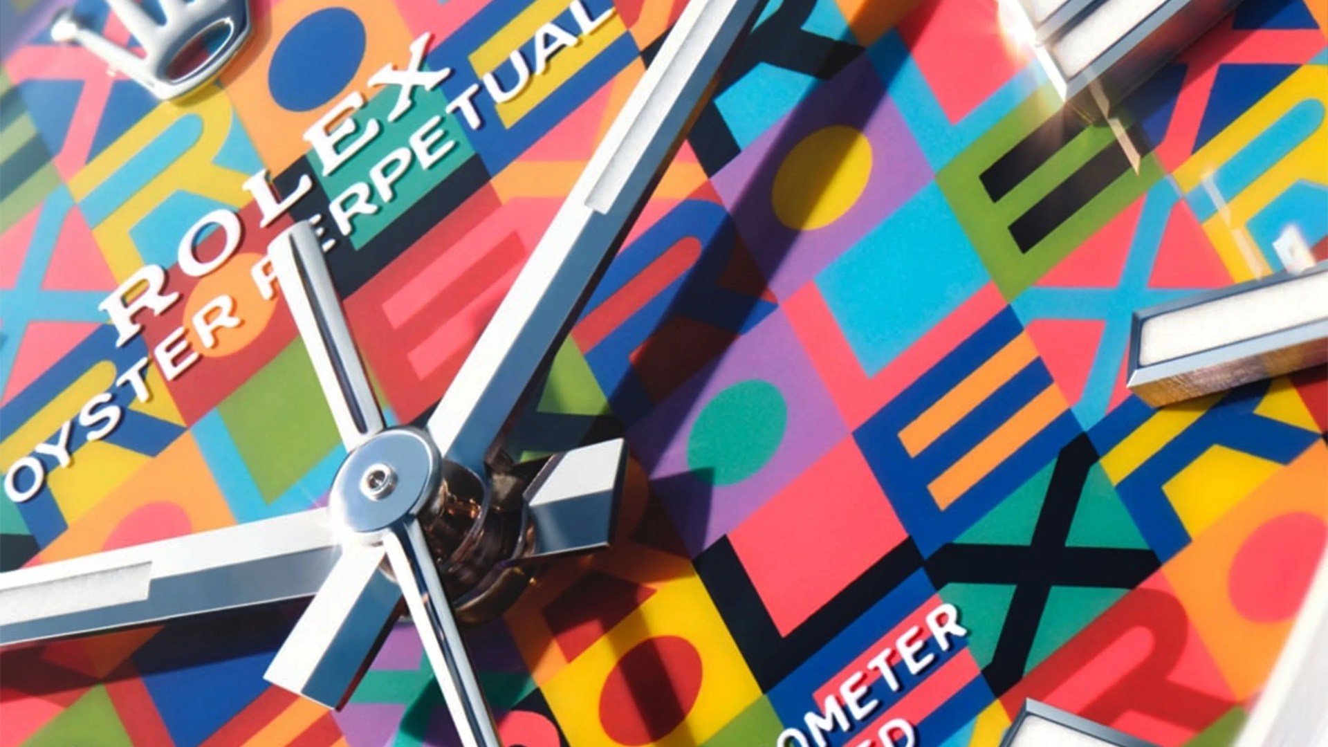 Close-up of a Rolex Oyster Perpetual watch face with colorful geometric patterns and silver hands.