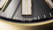 Close-up of a black Rolex watch dial with gold accents showing the text "100 YEARS" near the bottom.