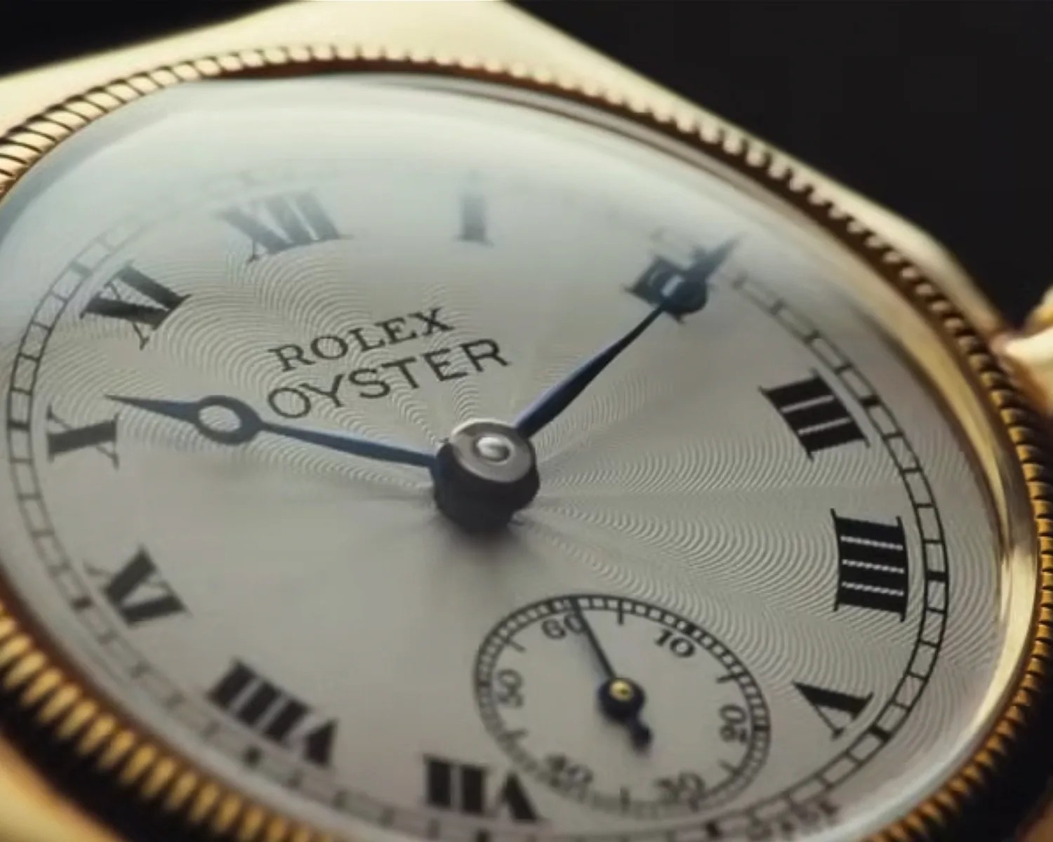 Close-up of a Rolex Oyster watch face with Roman numerals and a gold bezel.