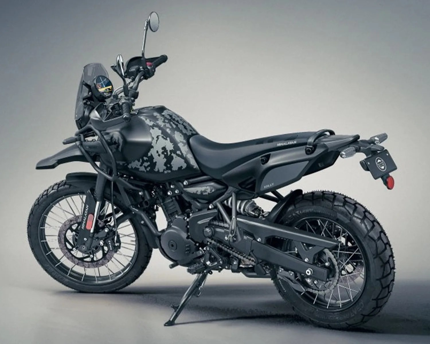 Matte black adventure motorcycle with camouflage-patterned fuel tank and knobby tires on a gray background.