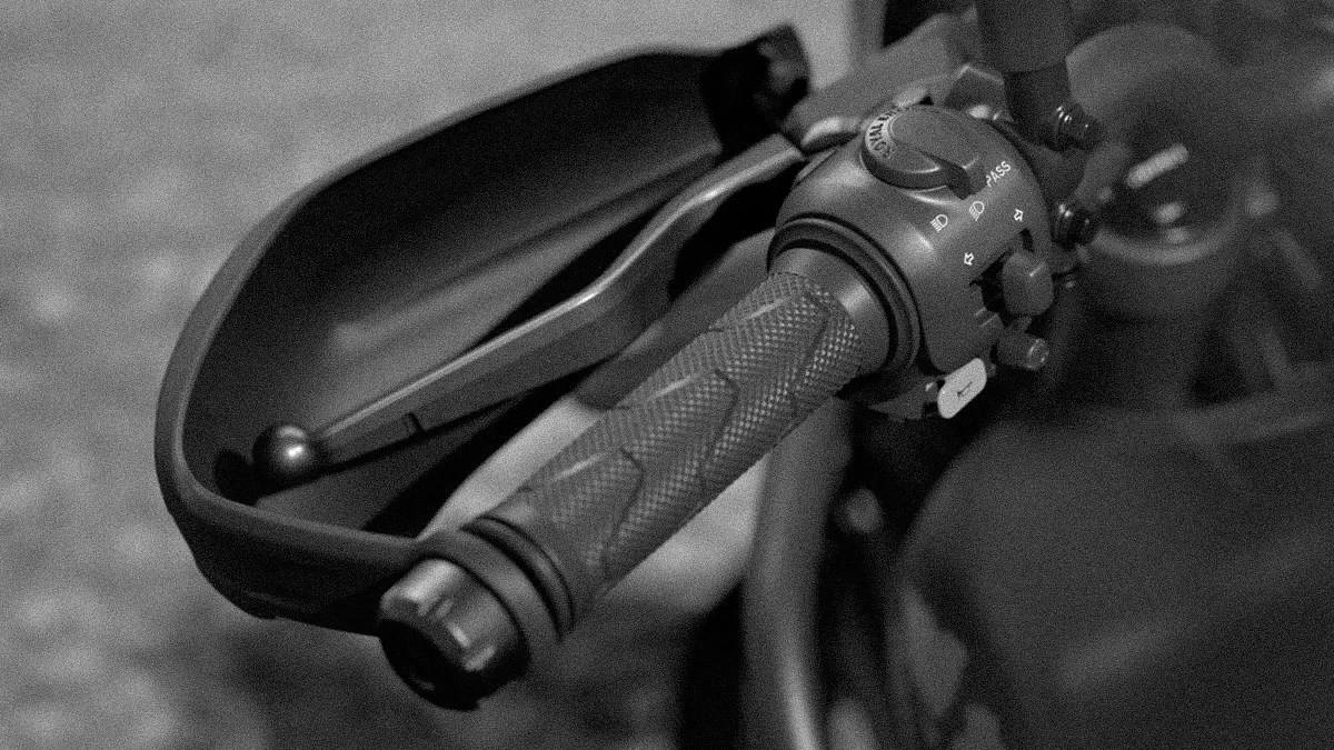 Close-up of a motorcycle handlebar grip with control switches and a brake lever.