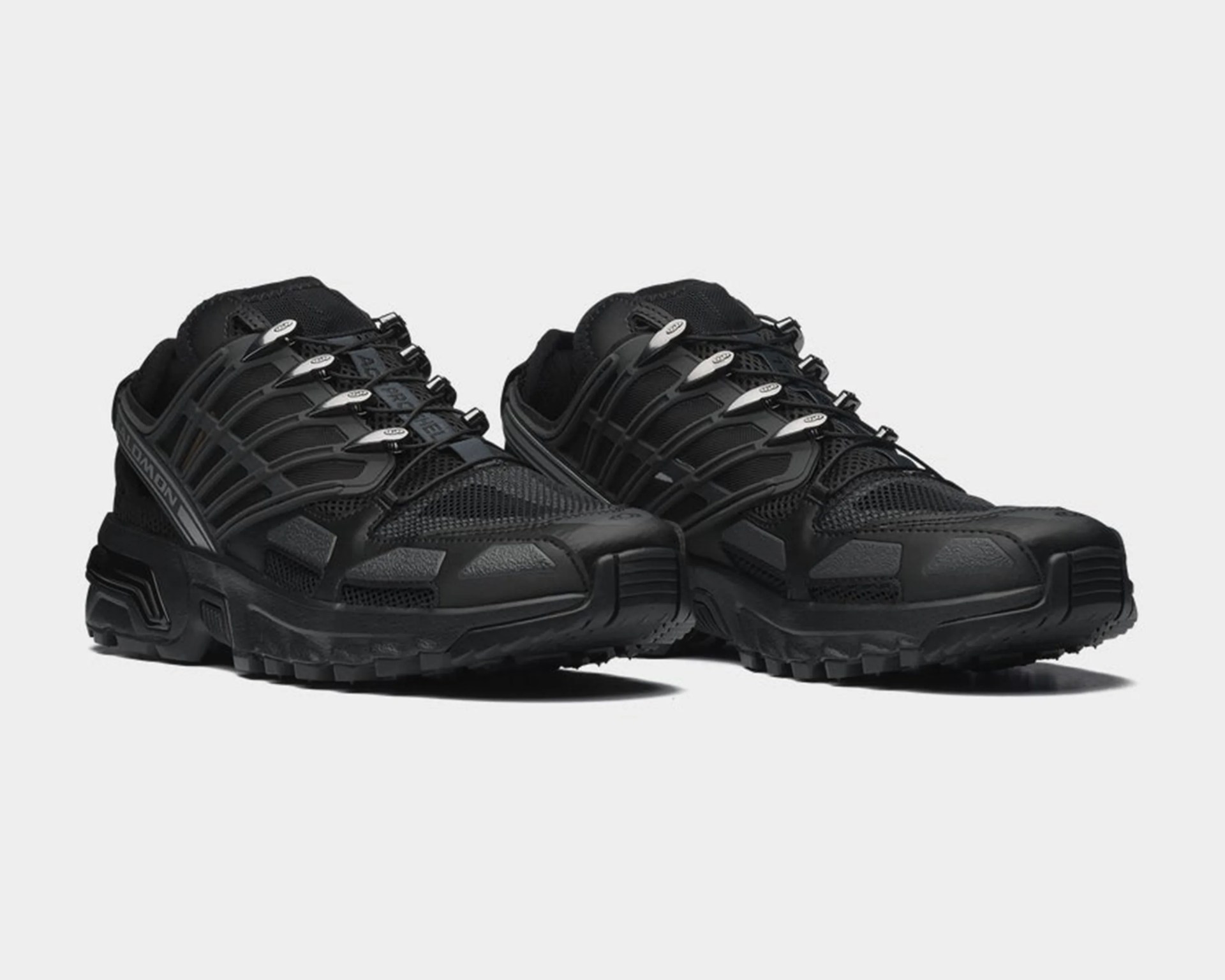 Pair of black Salomon trail running shoes with mesh and synthetic overlays and rugged soles.