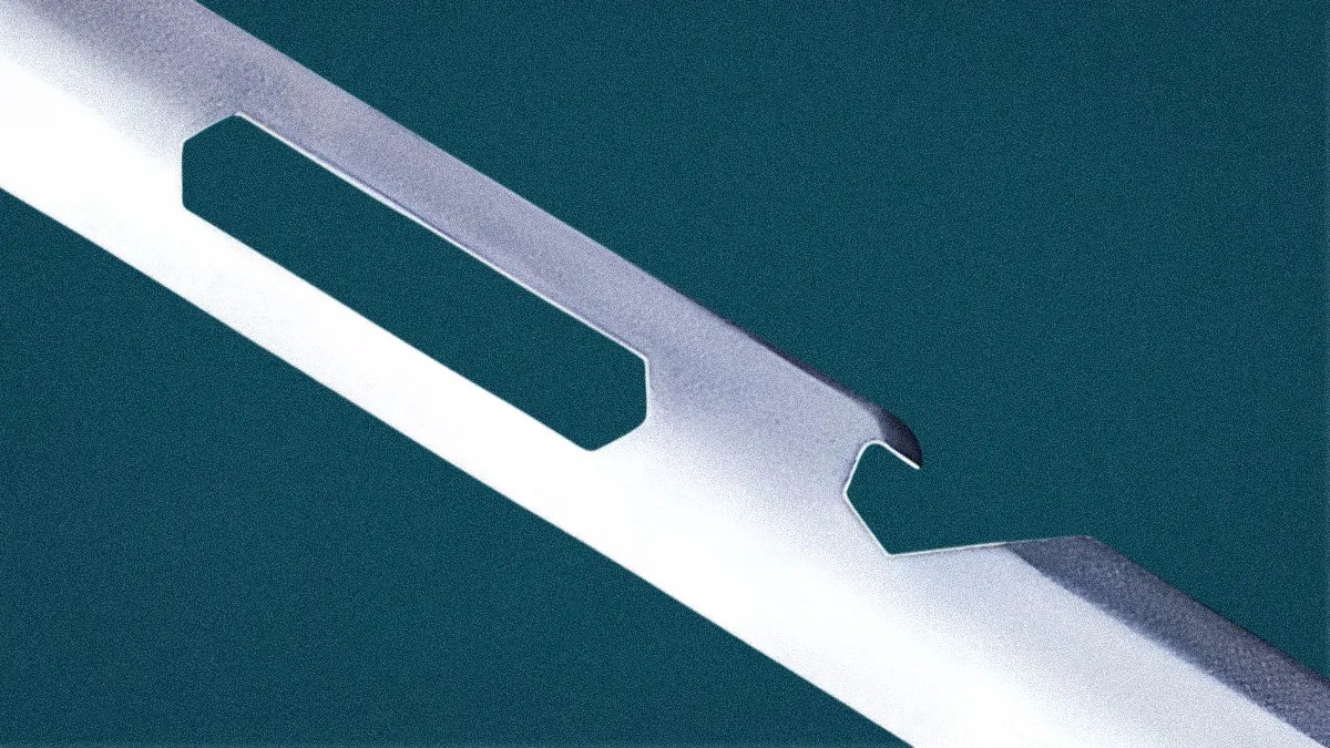 Close-up of a metallic blade with a rectangular cutout and a hooked notch on a teal background.