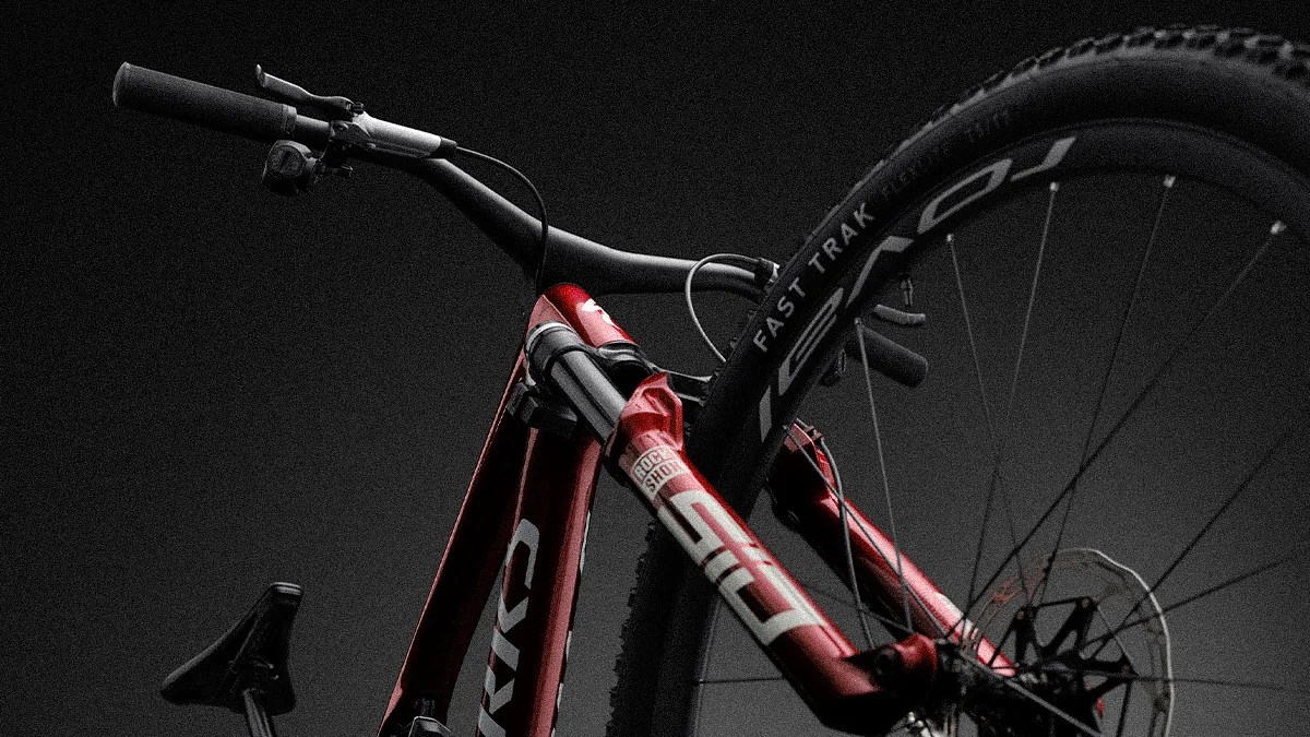 Close-up of a red mountain bike front fork and wheel with "RockShox" and "Fast Trak" branding on a dark background.