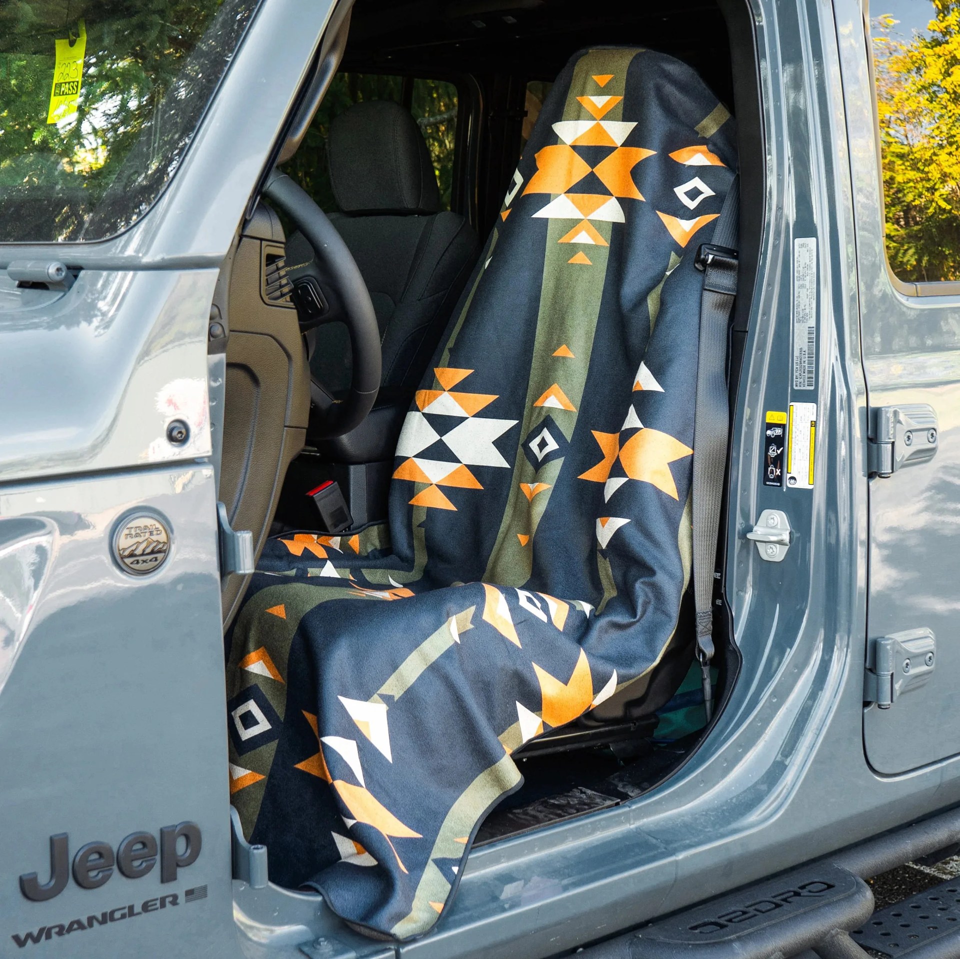 Jeep Wrangler front seat covered with a black, orange, white, and green geometric patterned blanket.