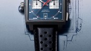 Square stainless steel watch with blue dial, red and white hands, and black perforated leather strap.