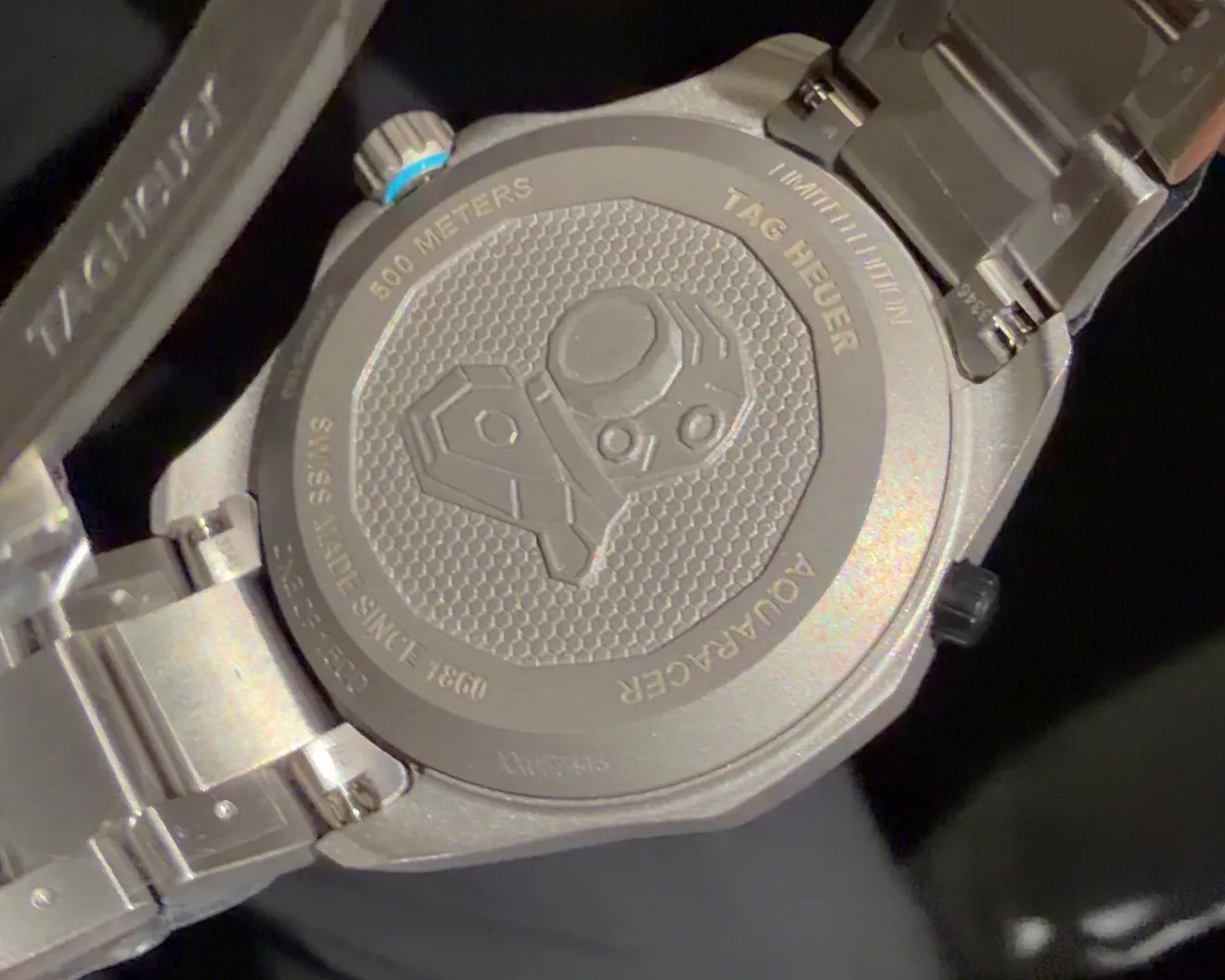 Silver TAG Heuer Aquaracer watch back with engraved diving helmet and text "500 meters," "Swiss made since 1860.