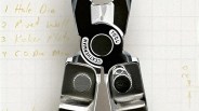 Close-up of a black and silver Leatherman multi-tool pliers on graph paper with handwritten notes.