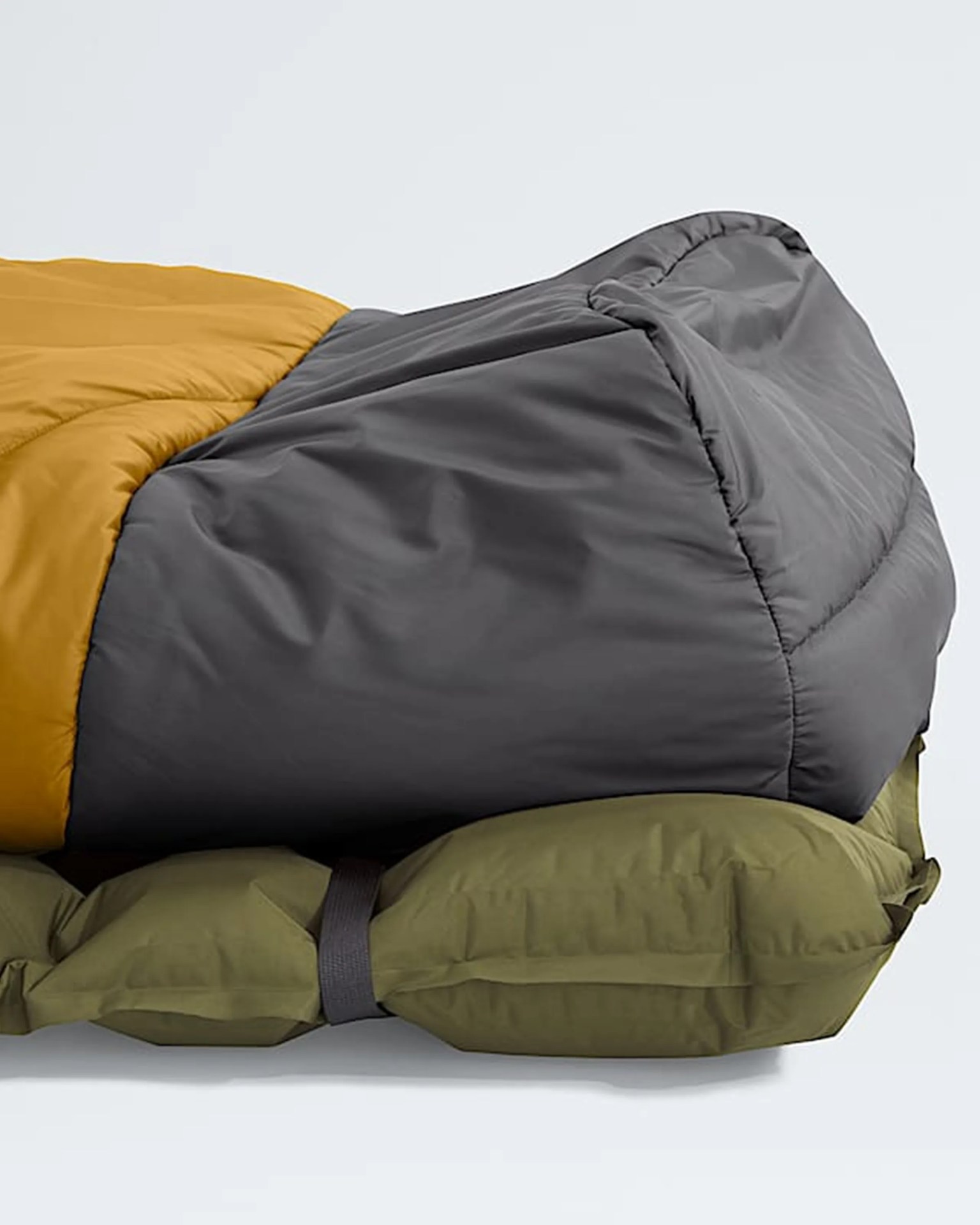 Close-up of a gray and mustard sleeping bag with an olive green sleeping pad underneath secured by a black strap.