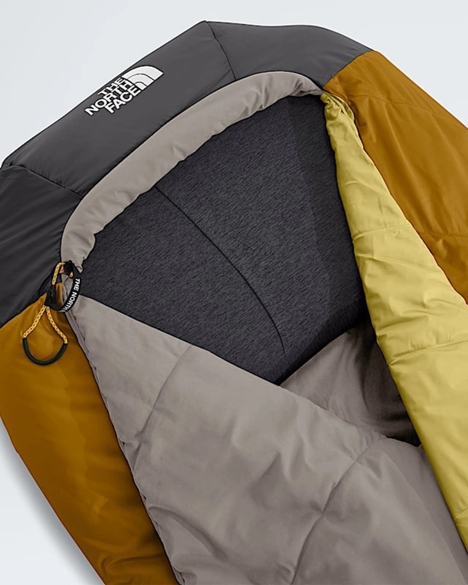 The North Face sleeping bag with black, mustard yellow, and beige sections, partially open to show the interior lining.