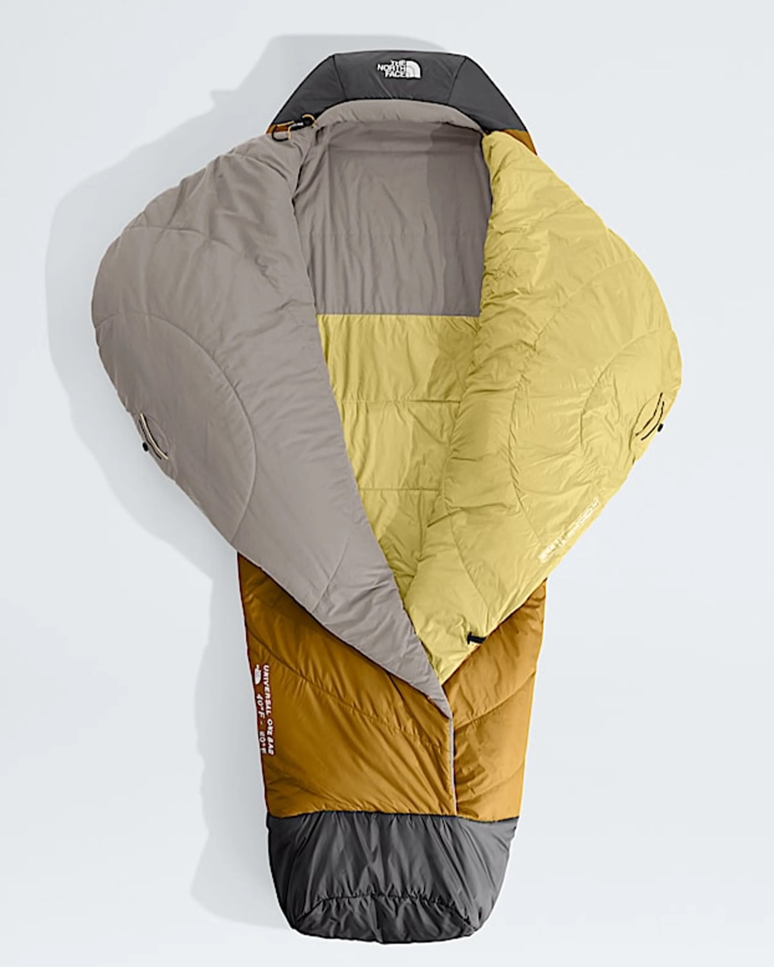 Mummy-style sleeping bag in mustard yellow, gray, and beige with The North Face logo on the hood.