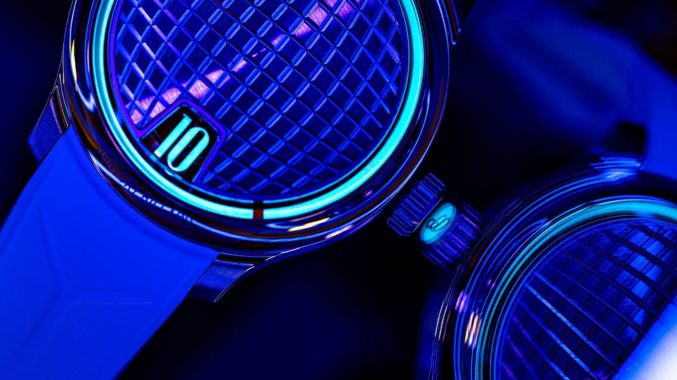 Close-up of two wristwatches with rubber straps and illuminated blue patterned dials showing the number 10.
