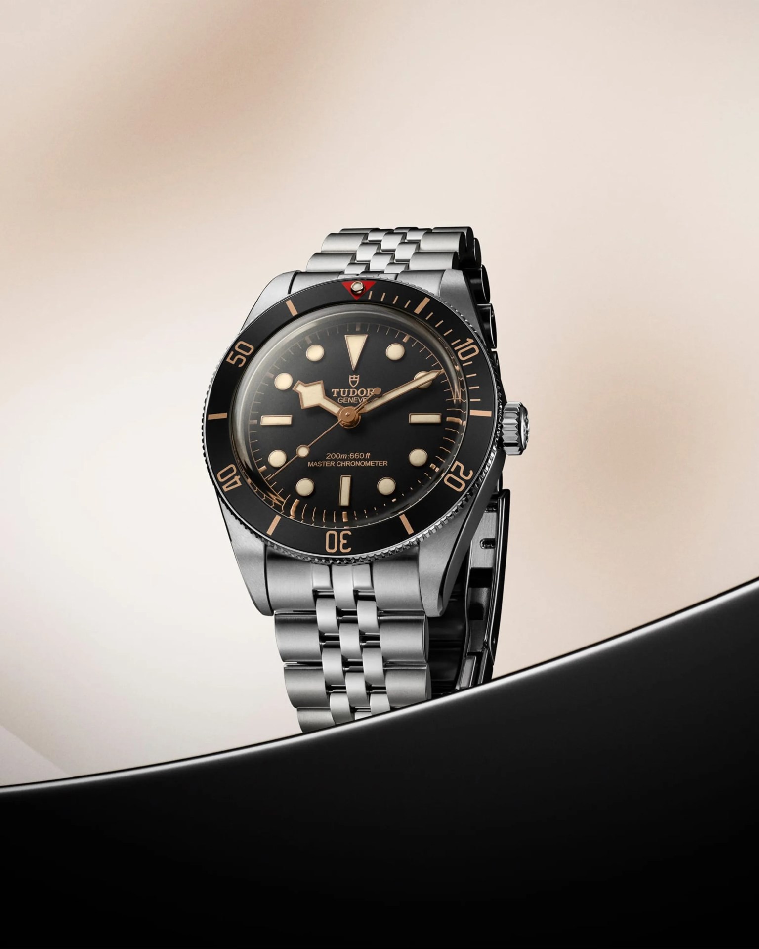 Stainless steel Tudor dive watch with black dial, beige markers, and rotating bezel on a metal bracelet.