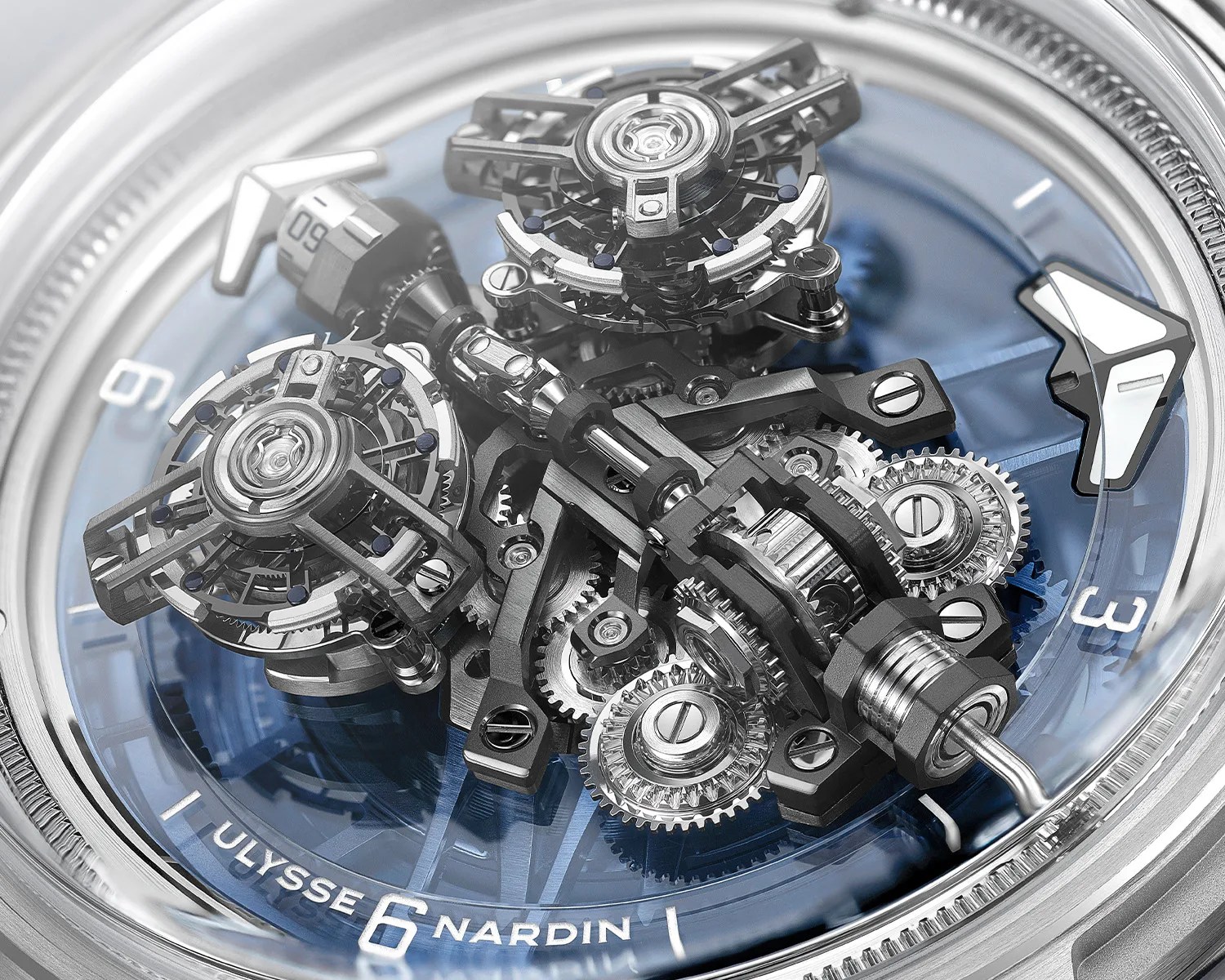 Close-up of a Ulysse Nardin watch dial showing intricate mechanical gears and components with a blue background.