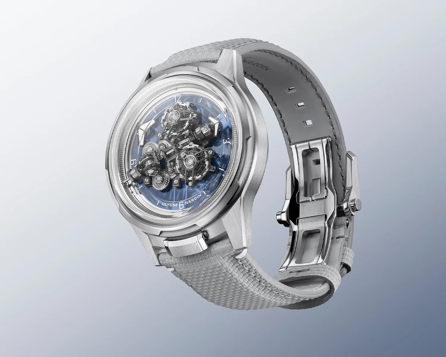 Silver Ulysse Nardin wristwatch with exposed mechanical gears and a textured light gray strap.