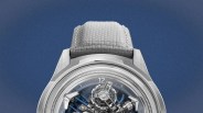 Silver wristwatch with a transparent dial showing intricate mechanical gears and a light gray textured fabric strap.