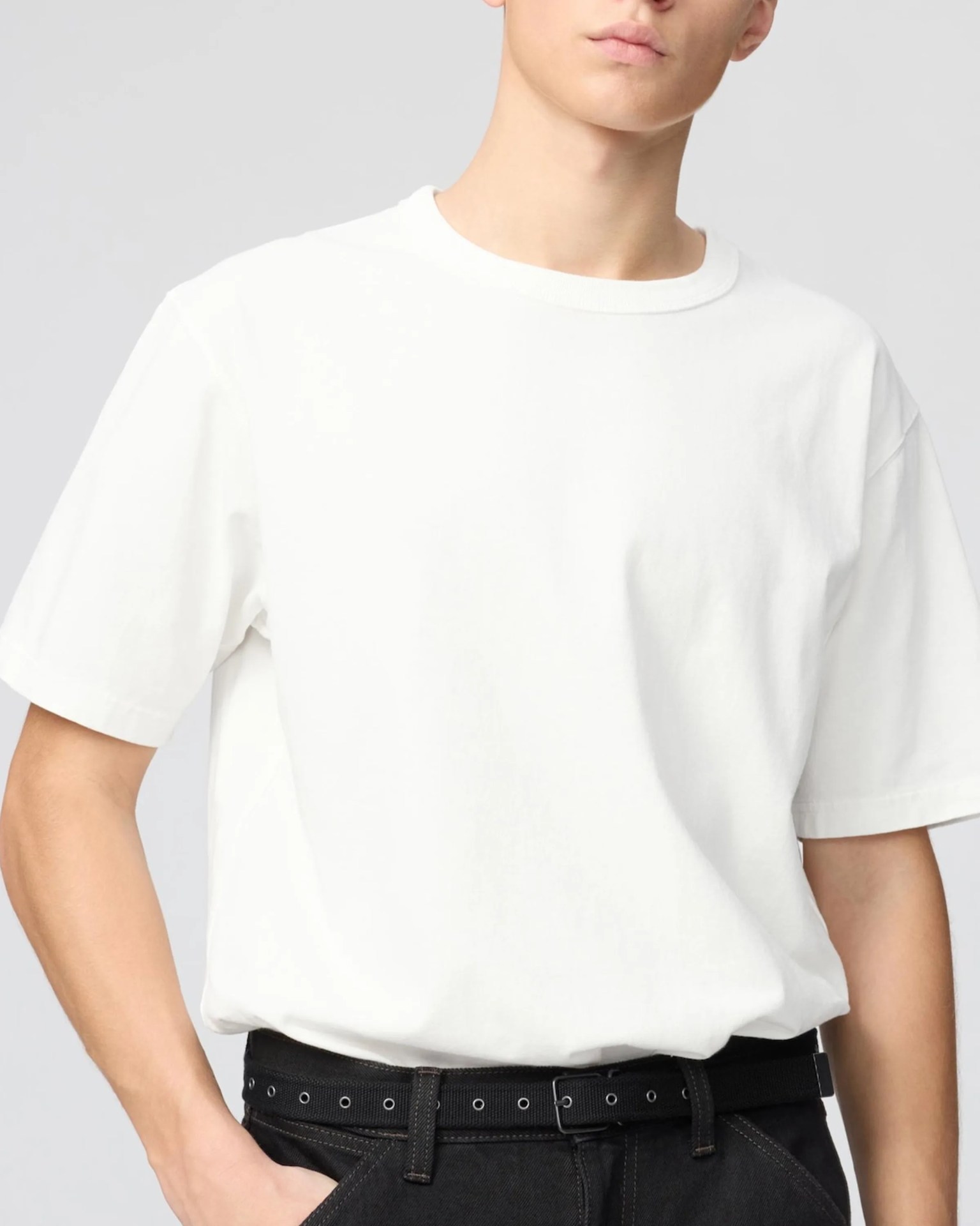 White short-sleeve crew neck T-shirt worn tucked into black jeans with a black belt.