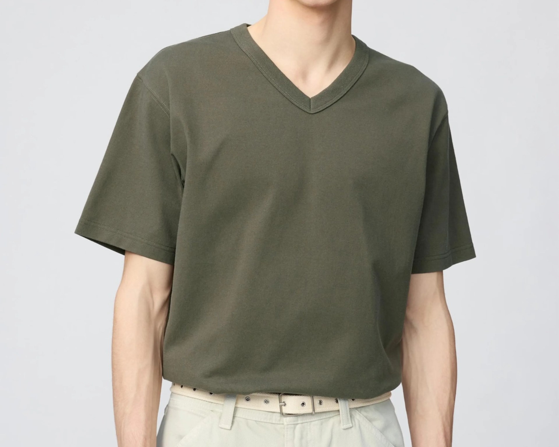 Olive green V-neck short-sleeve T-shirt worn tucked into light beige pants with a beige belt.