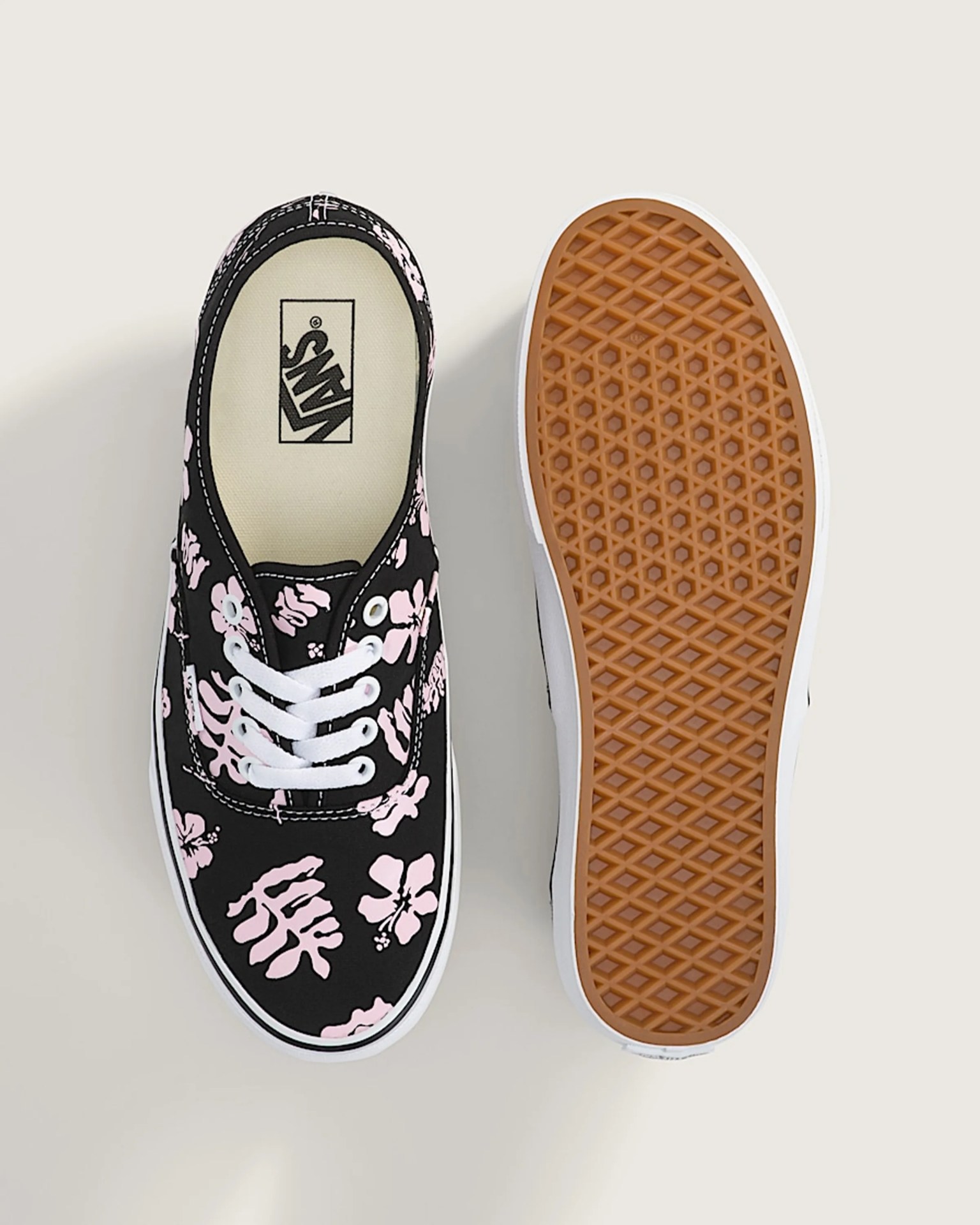 Pair of black Vans sneakers with pink floral print, white laces, and gum rubber waffle soles.