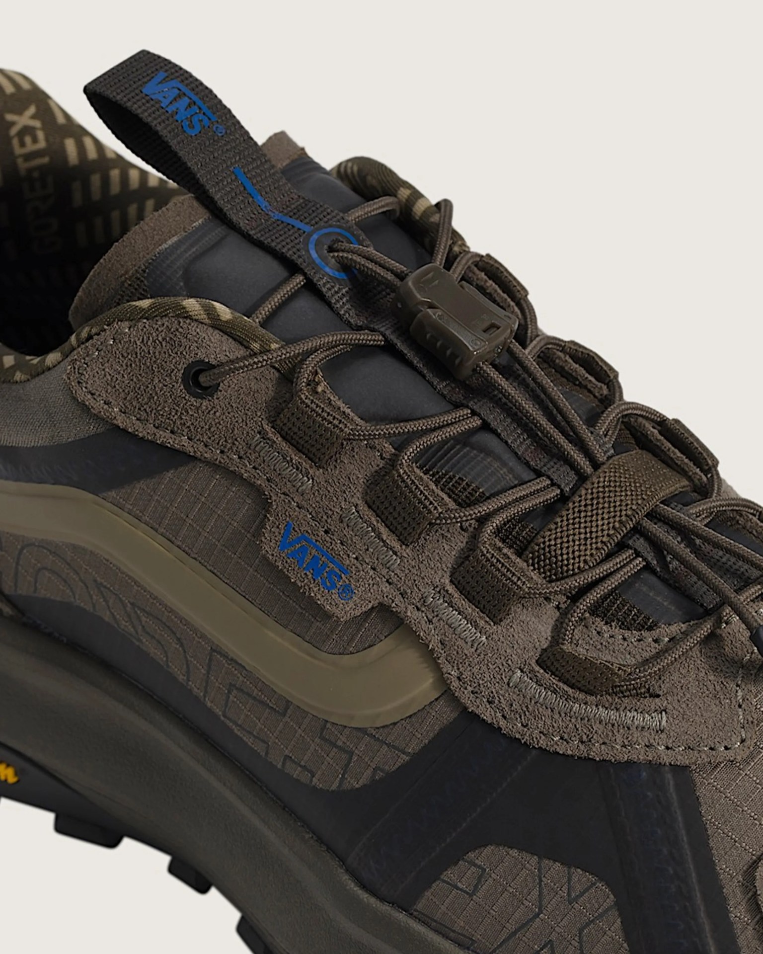 Close-up of a brown Vans Gore-Tex sneaker with blue Vans logo and toggle lace system.