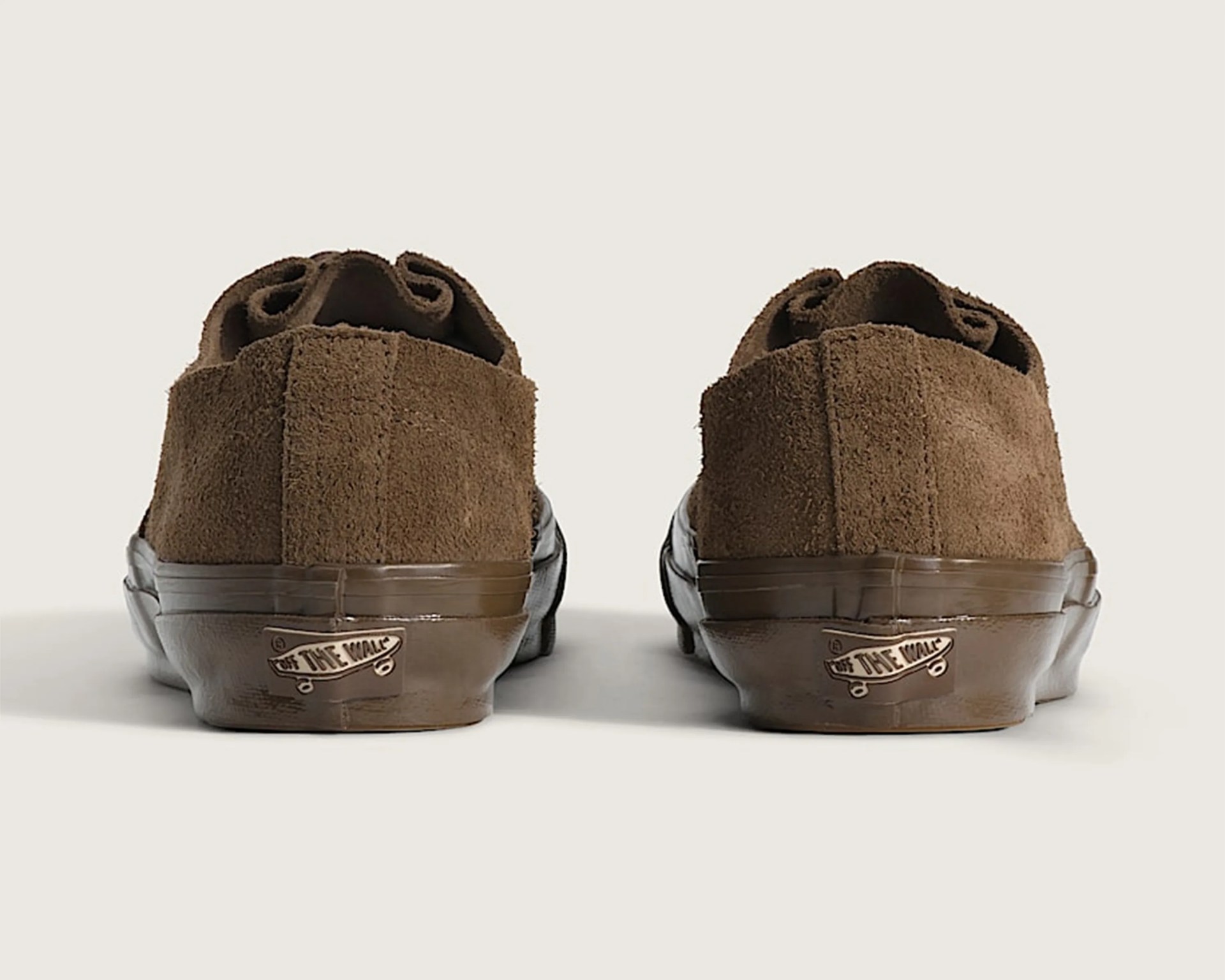 Pair of brown suede Vans sneakers viewed from the back with brown rubber soles and "Off The Wall" logo.