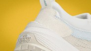 Close-up of the heel of a white Vans sneaker with textured fabric and a "Vans Off The Wall" logo on the sole against a yellow background.