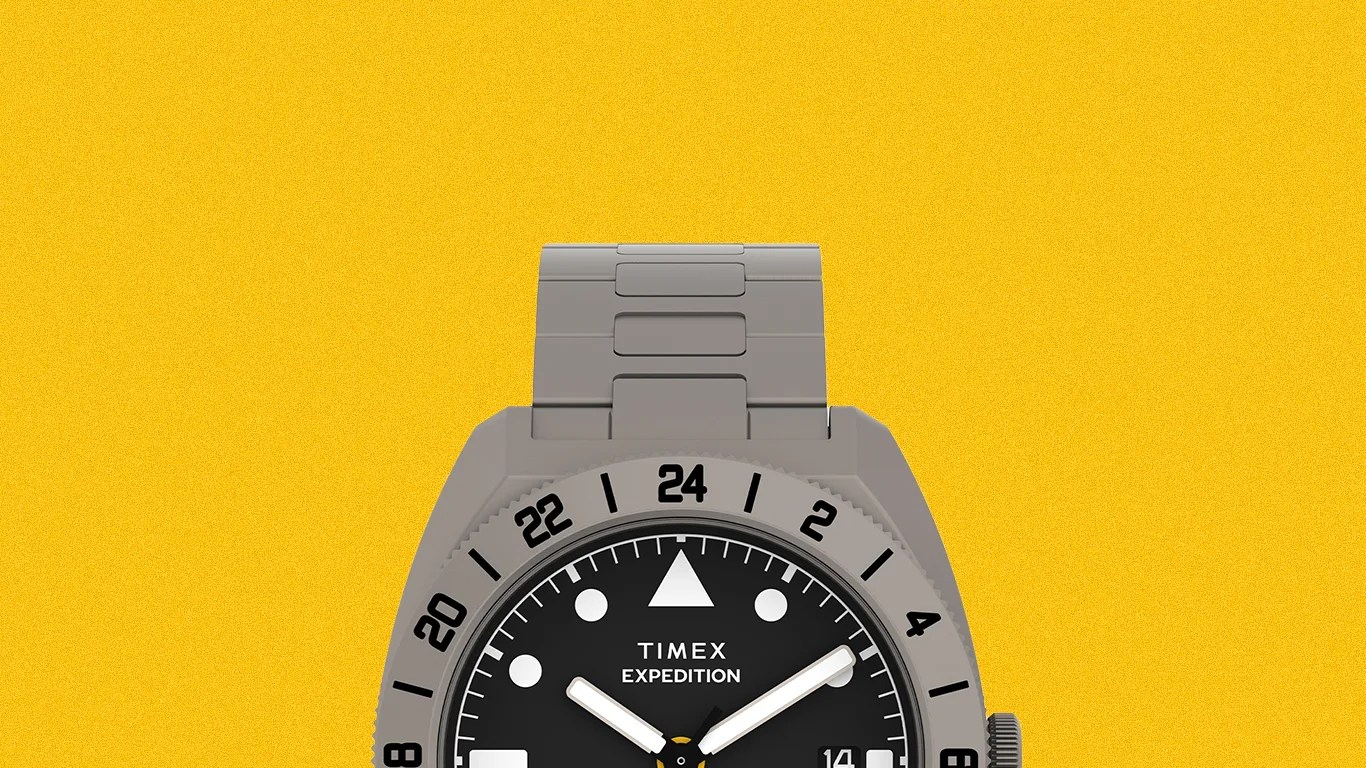 Gray Timex Expedition watch with black dial, white hour markers, and 24-hour bezel on a yellow background.