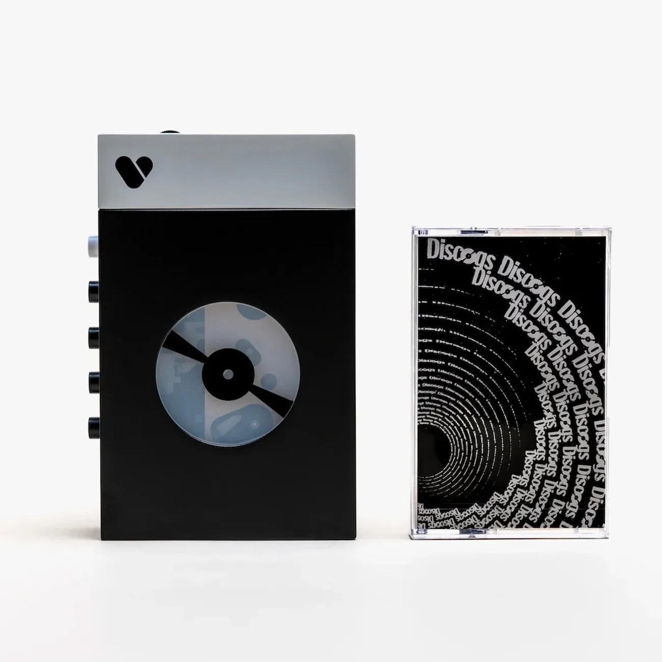 Black and silver rectangular device with a circular window next to a black cassette tape case with white "Discogs" text spiraling on the cover.